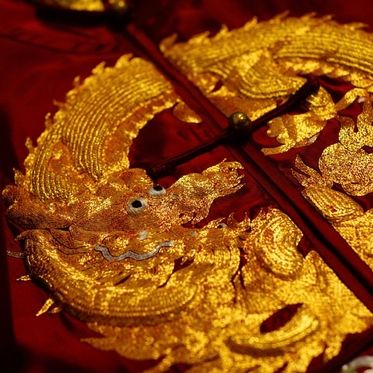 Detailed view of a gold 3-d hand-embroidered dragon. 