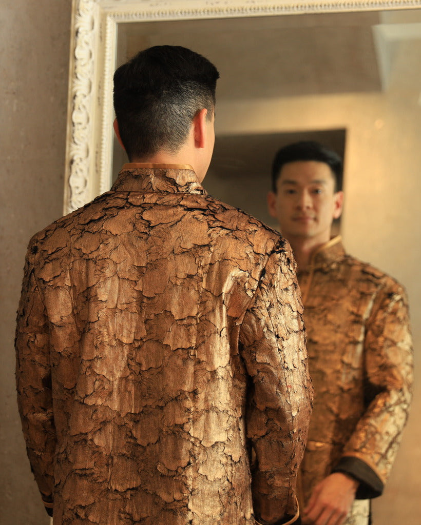 Back view of premium gold Tang suit featuring intricate leaf texture and black silk lining for a modern, elegant look.