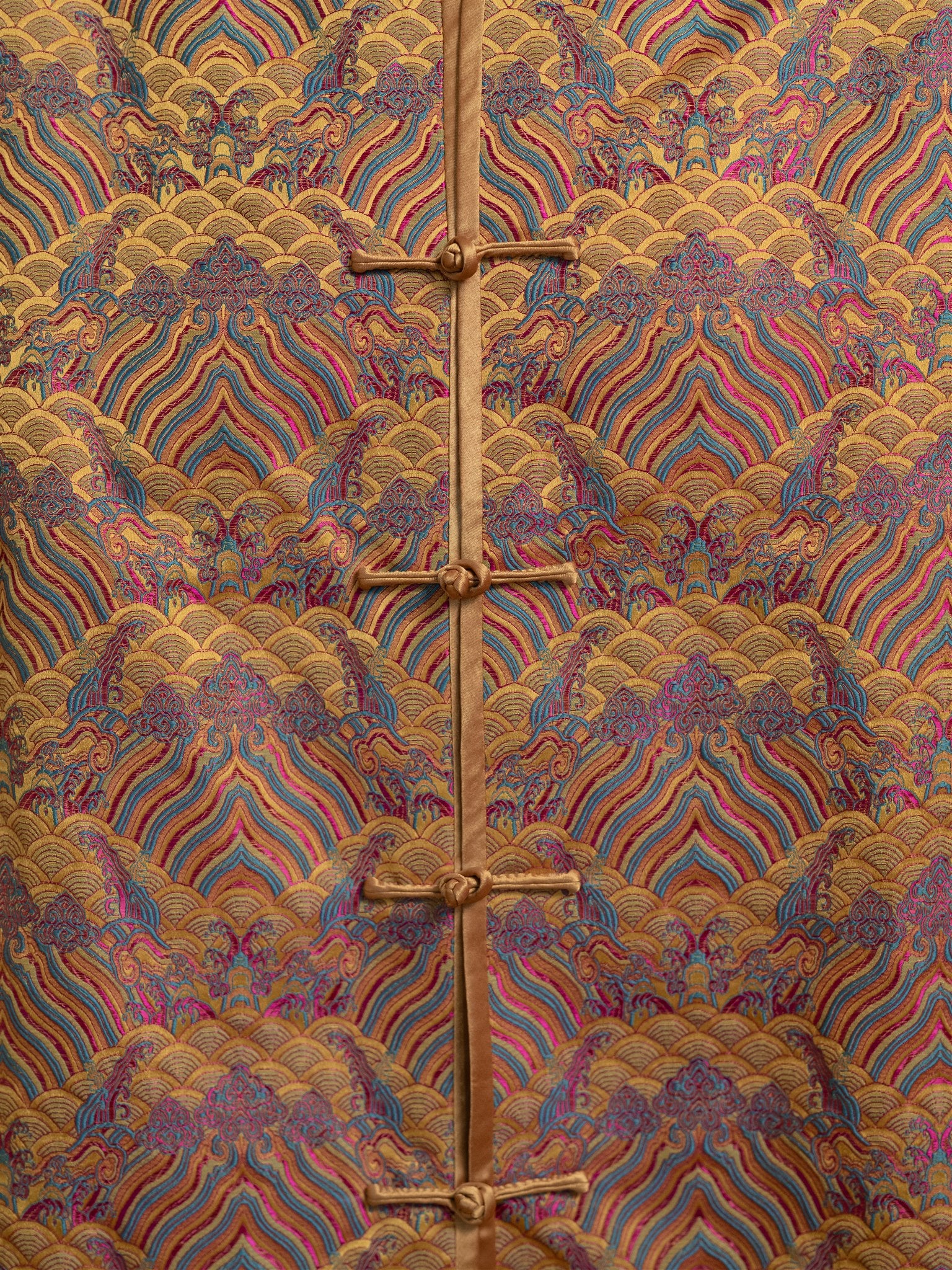 Close-up of sea wave embroidery on gold silk Tang suit.