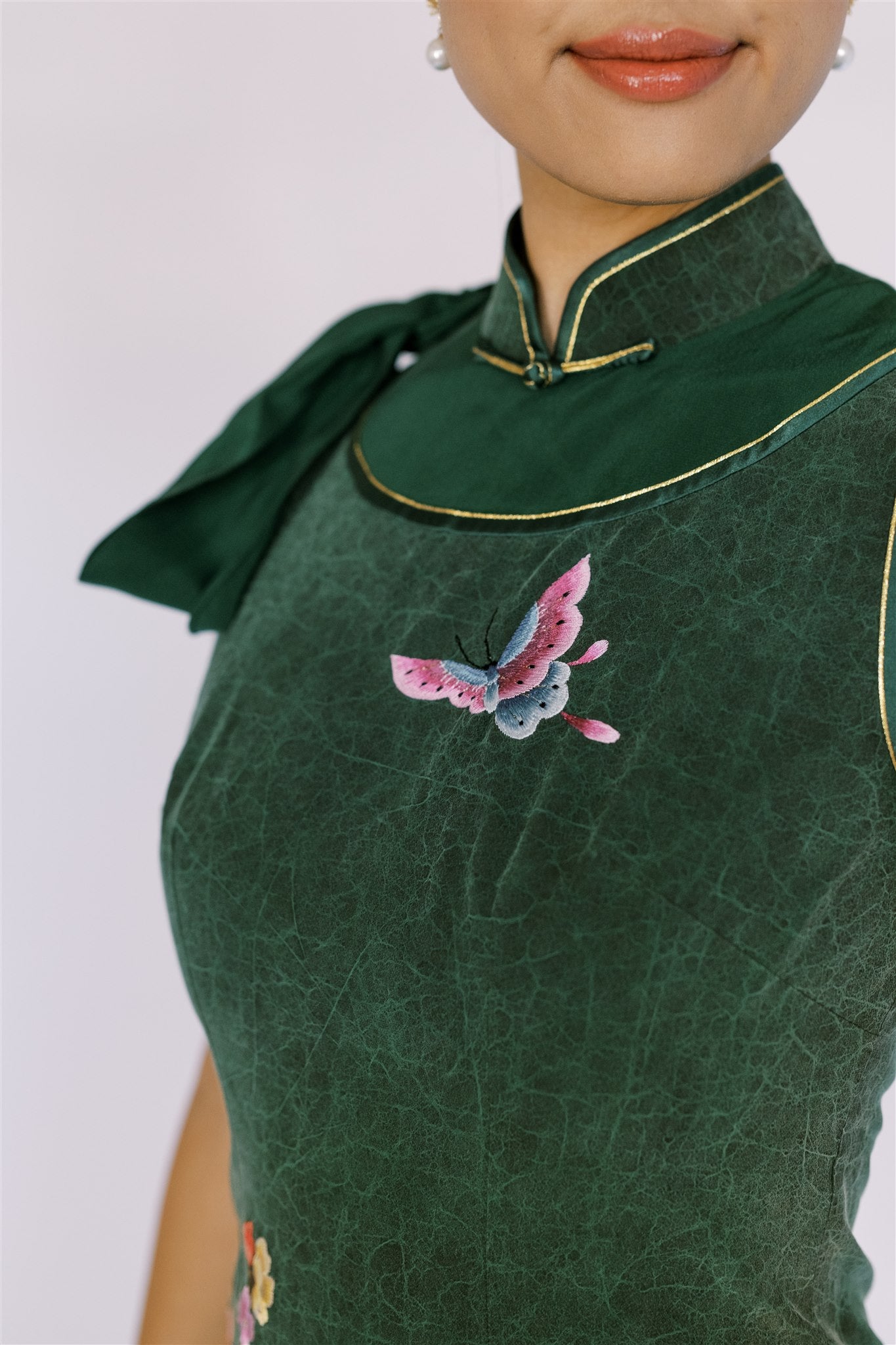 Detailed view of the hand-embroidered butterfly on an elegant emerald green Qipao in Cheongsam style, a perfect choice for summer nights, combining modern aesthetics with cultural heritage.