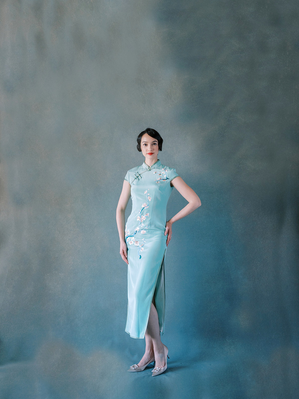 Front view of green silk Qipao with hand-embroidered cherry blossoms.