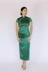 Front view of a woman wearing emerald green silk Qipao with traditional Pankou Knot.