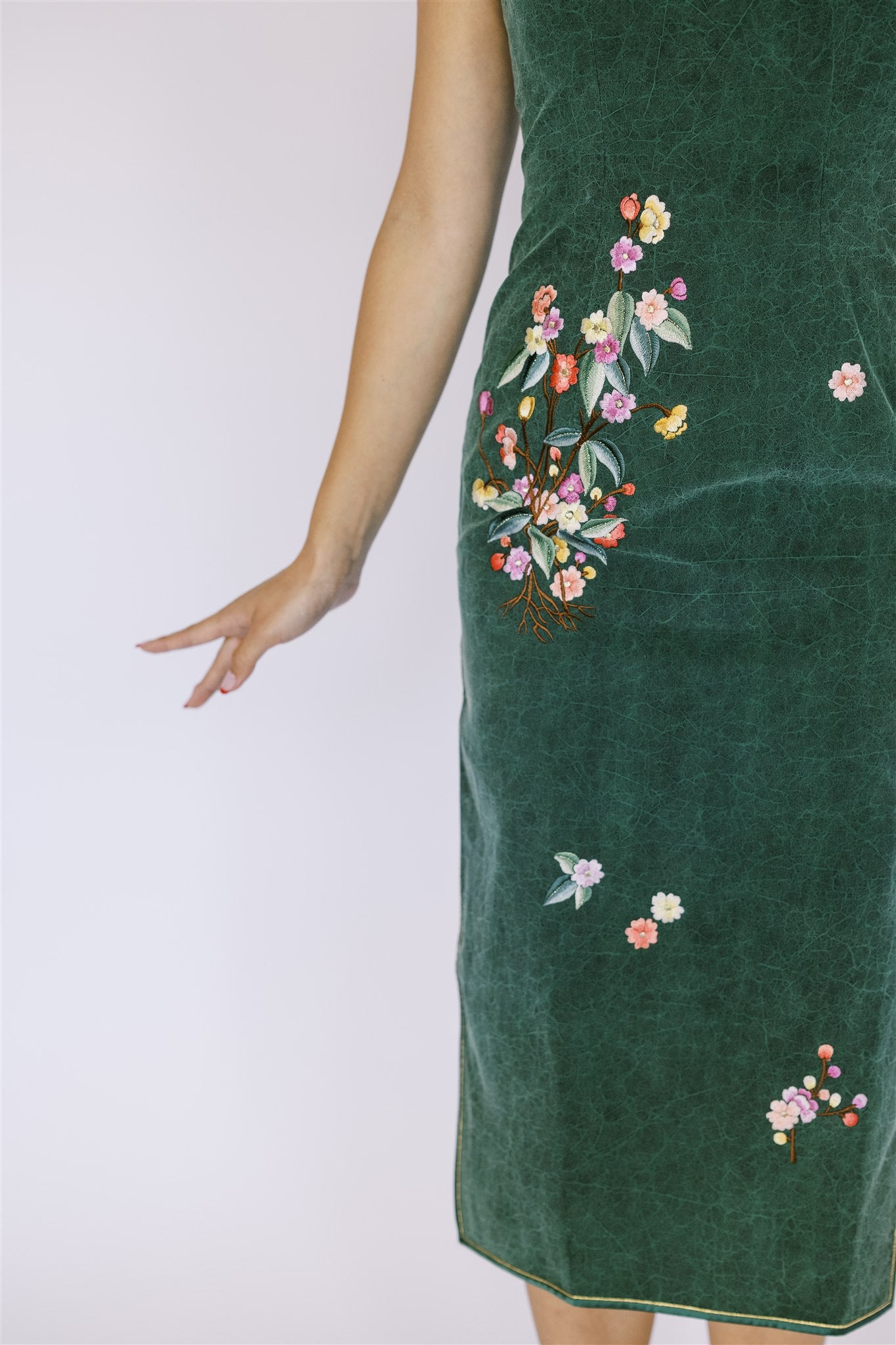 A woman wearing emerald green silk Qipao with floral embroidery