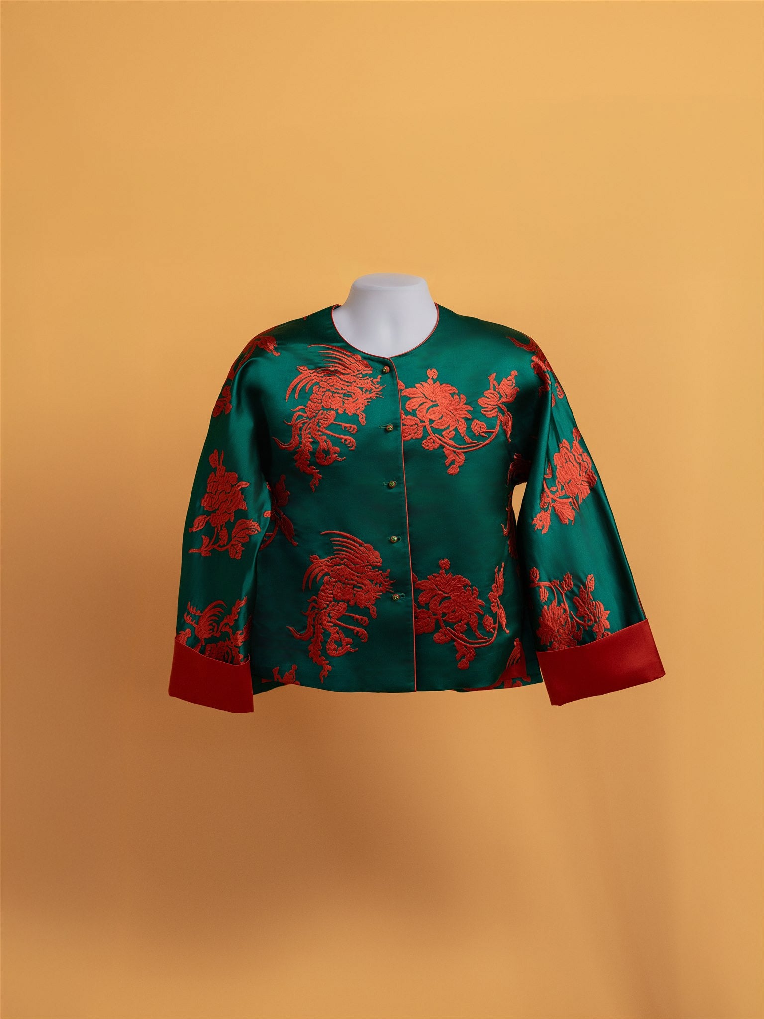 Front view of a green silk round neckline modern tang suit with orange peony embroidery, perfect for every day wear. 