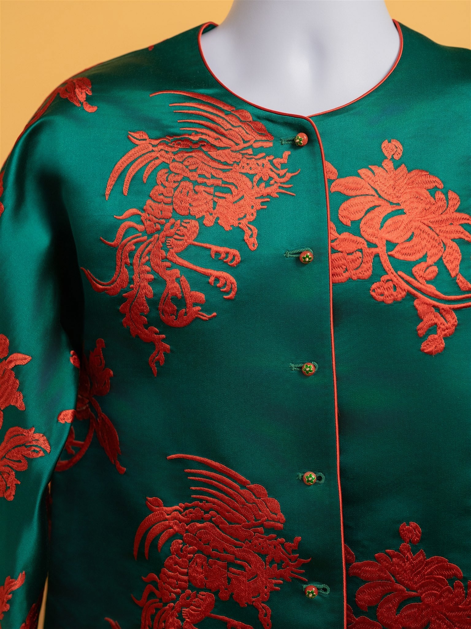 A detailed image of peony embroidery and buttons on a green silk tang suit for woman. 