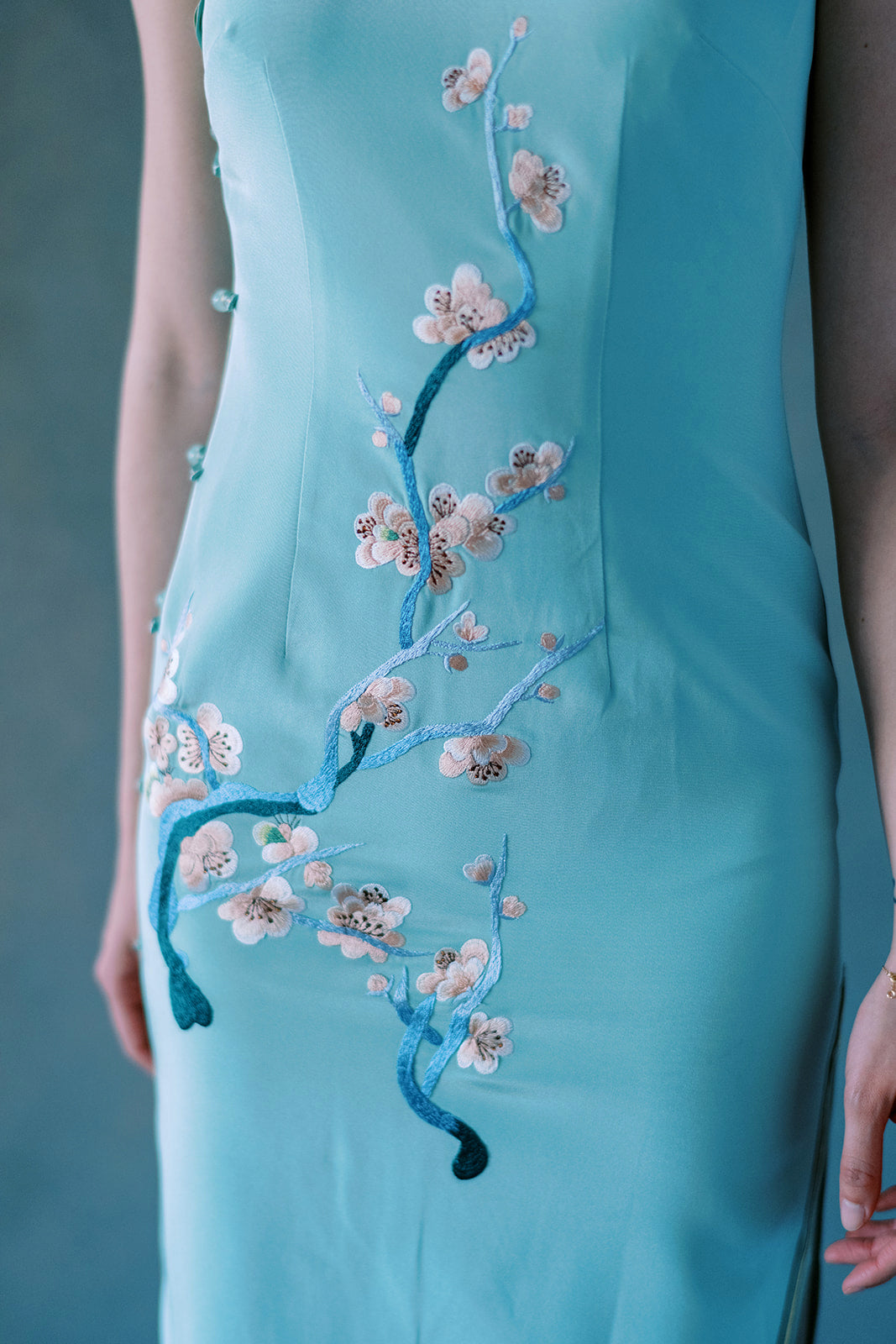 Embroidery detail of cherry blossom motifs on green silk Qipao dress.
