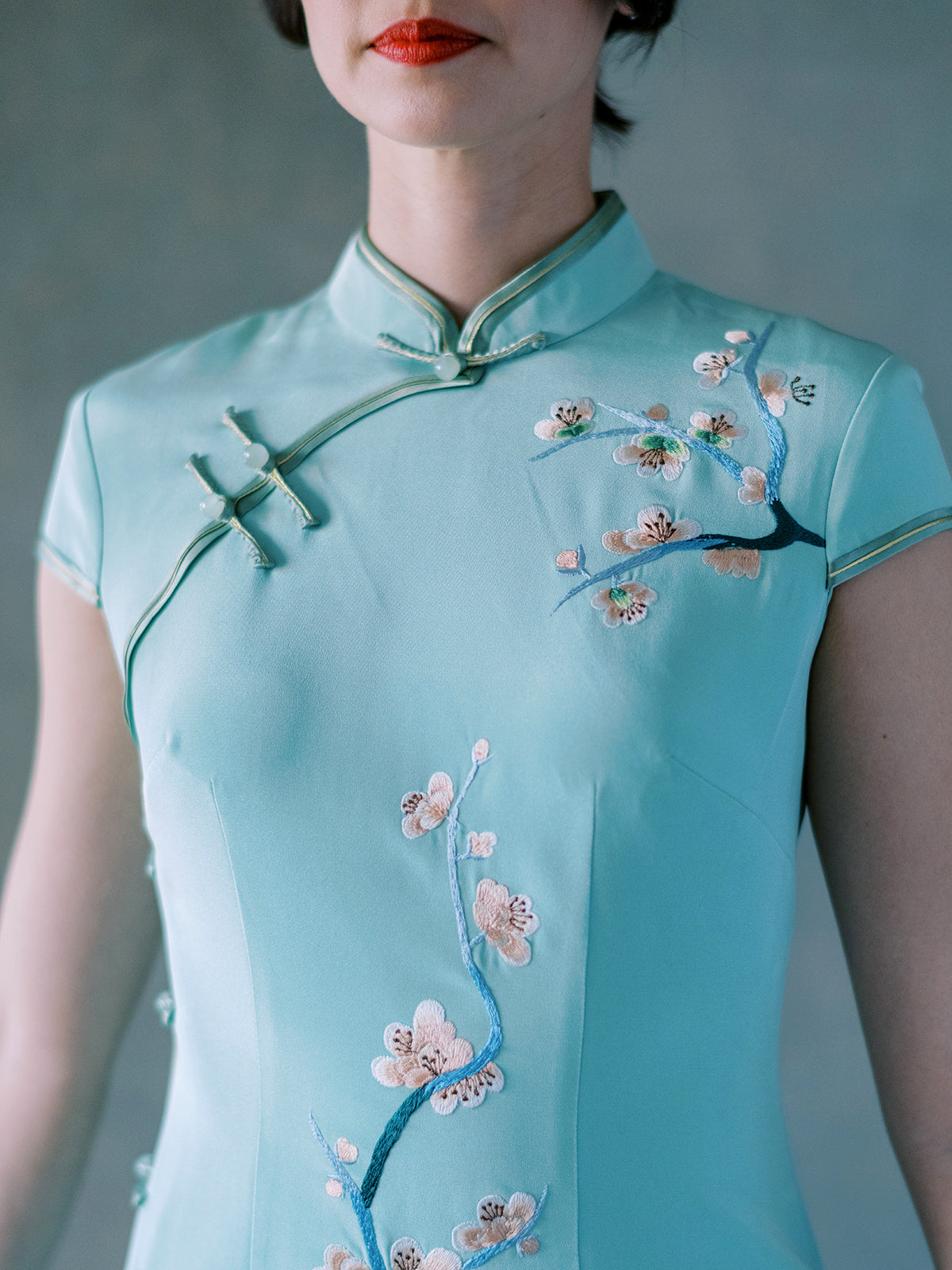 Pankou knot detail of cherry blossom motifs on green silk Qipao dress.