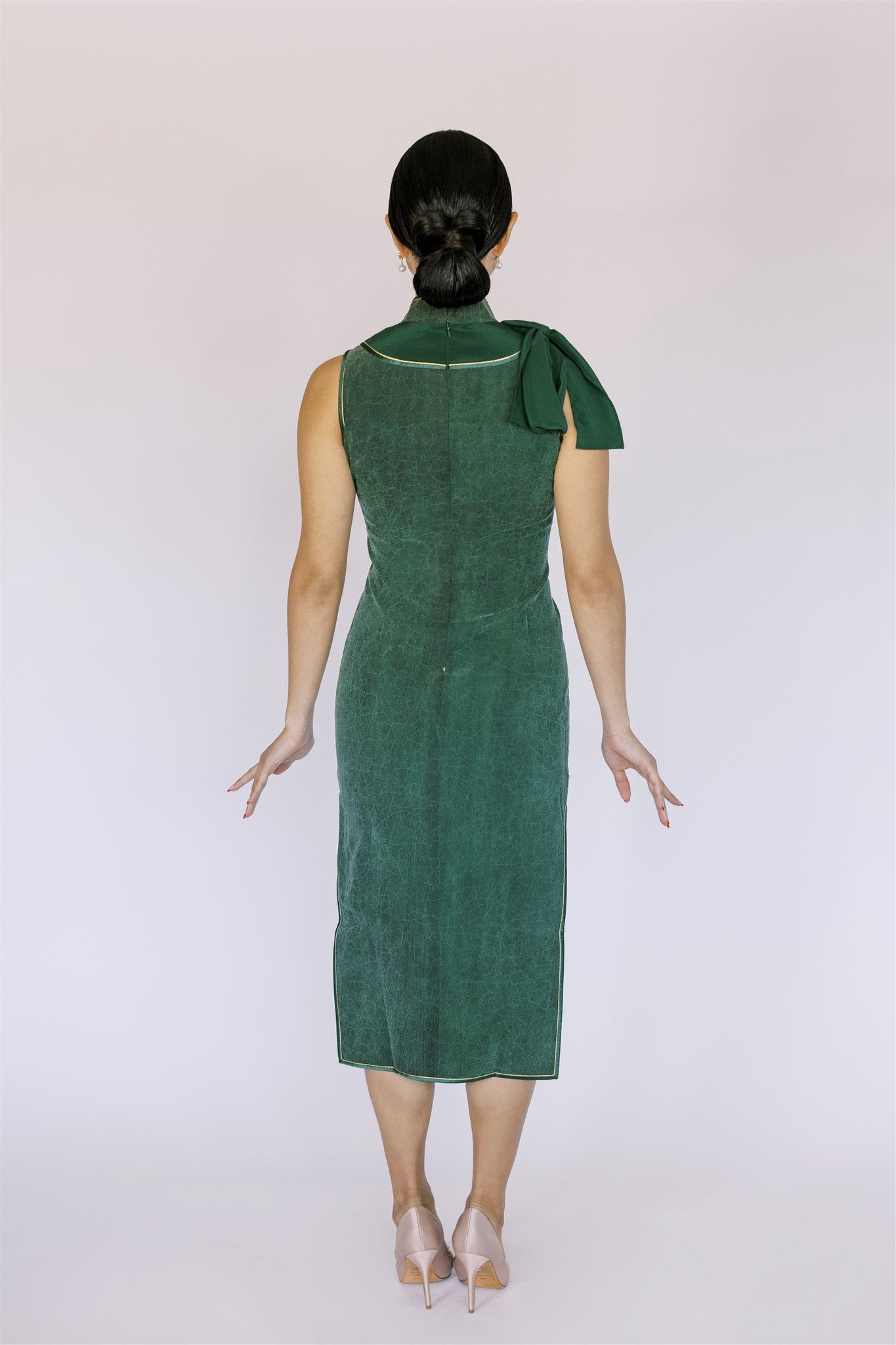 A woman wearing green silk qipao mid-calf length with silk ribbon