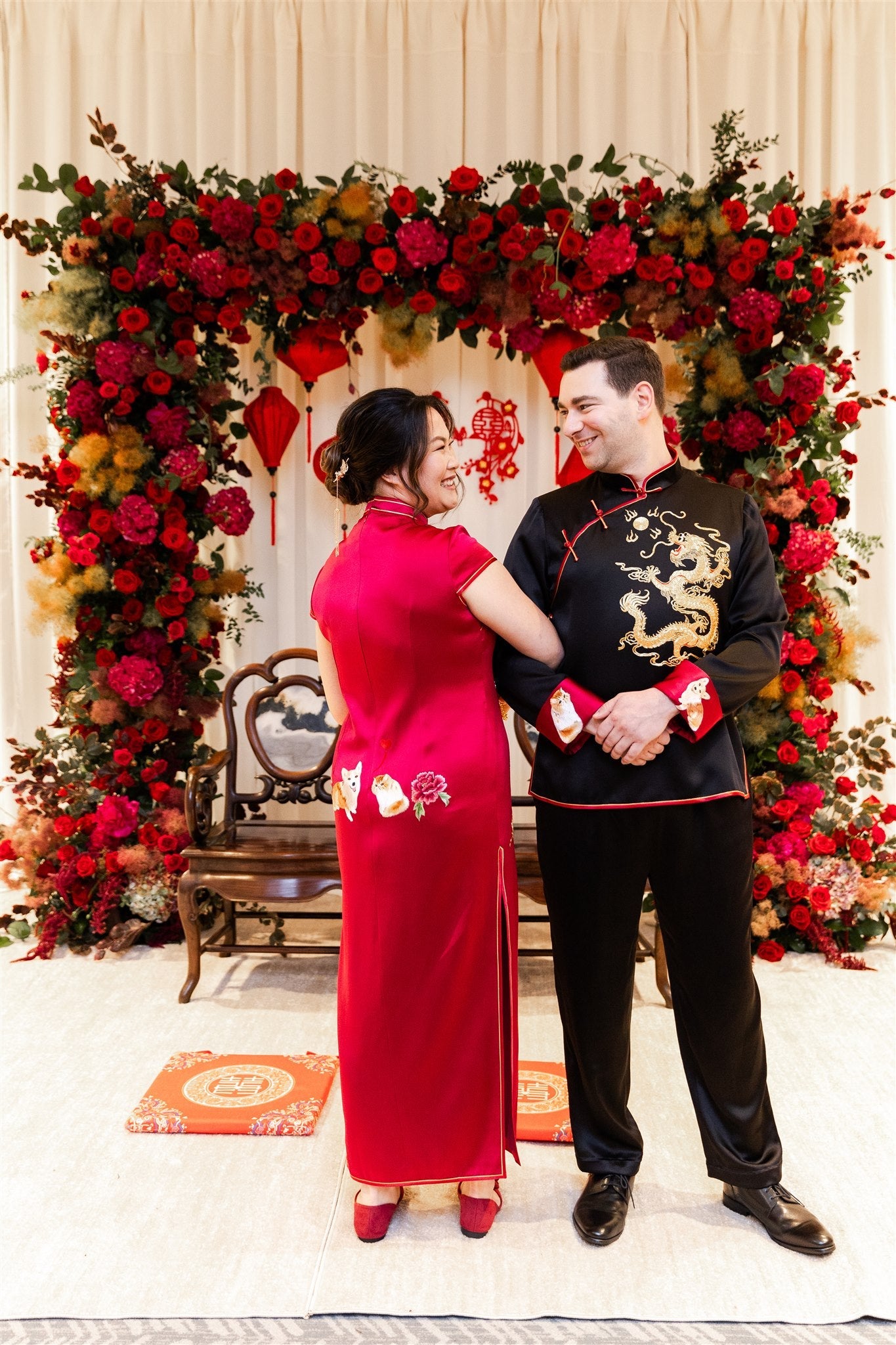 Front view of a groom wearing a black Tang suit with matching pants and gold dragon embroidery at his wedding.