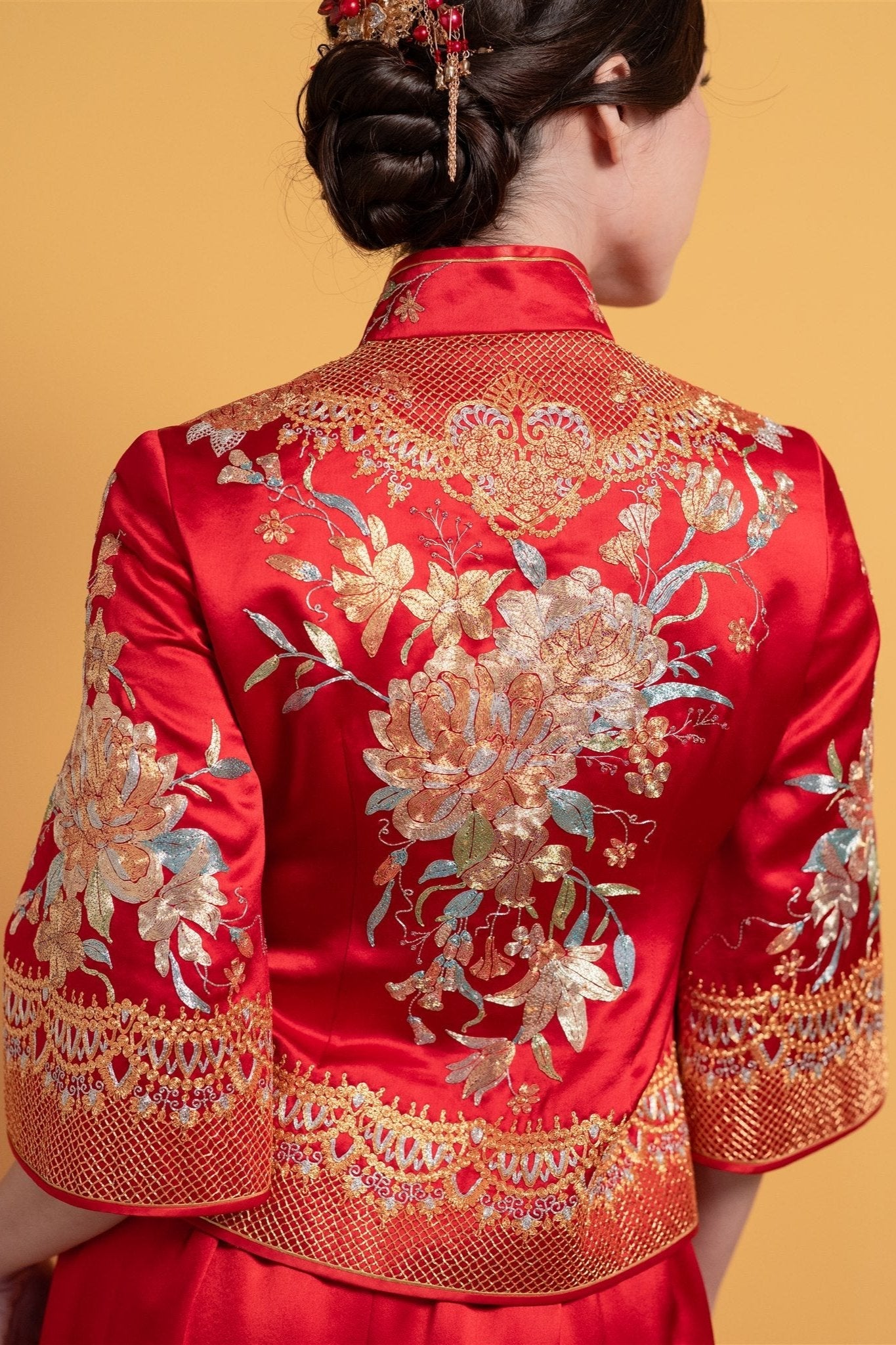 Close-up detail of the top, peony embroidery on the fitted top of a red Chinese tea ceremony Xiu He Fu dress.