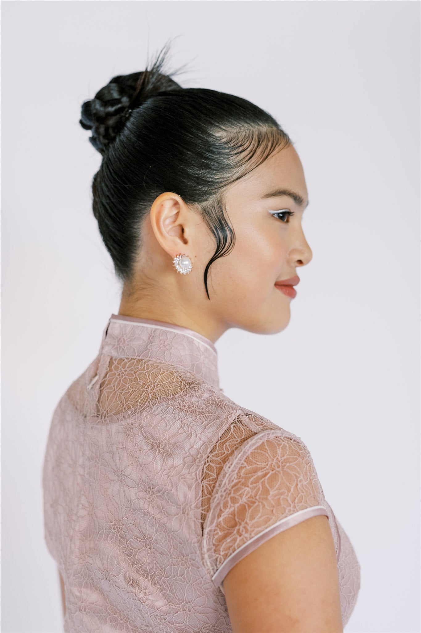 A girl wearing a blush pink lace modern Qipao for her graduation