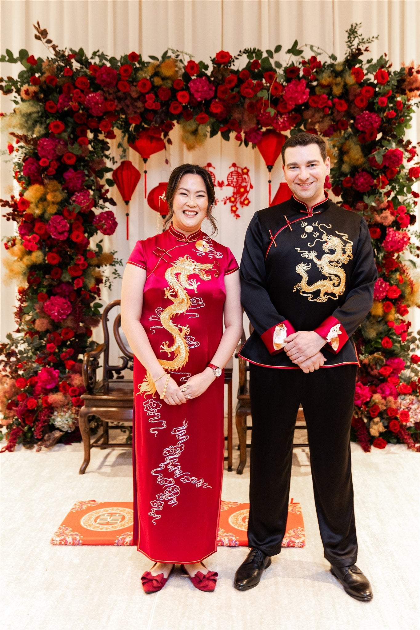 A bride is wearing red Chinese Wedding Dress with dragon embroidery and a groom is wearing matching black tang suit with gold dragon embroidery