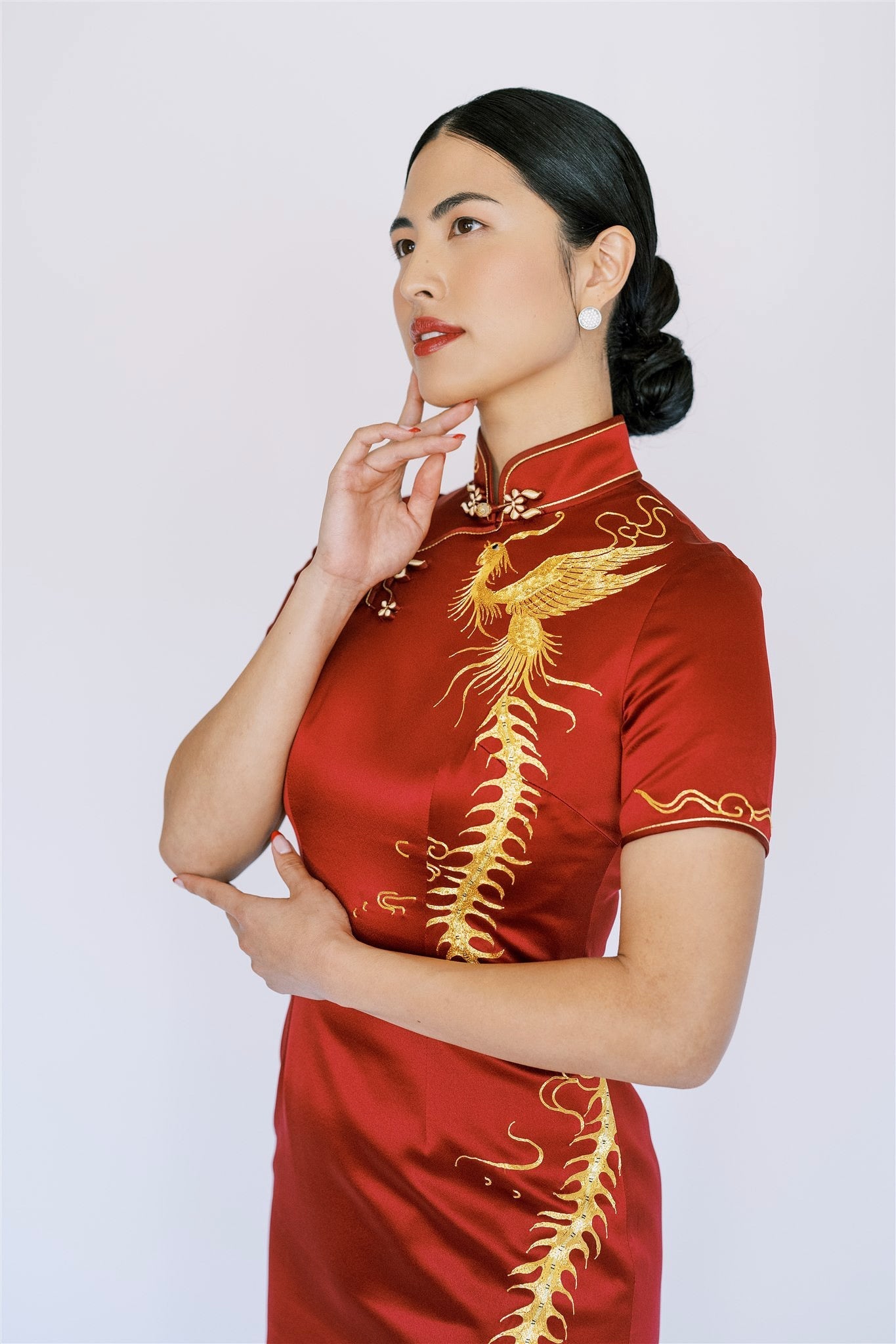 A woman wearing wine red wedding Qipao with gold phoenix for minimalist bride