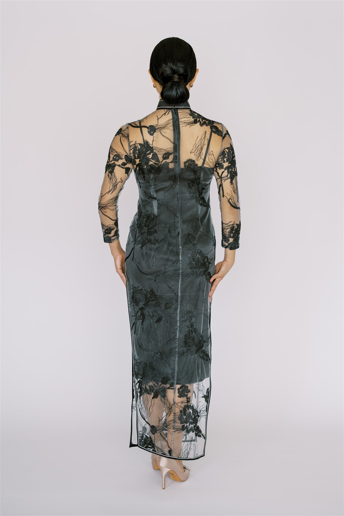 A back view of a long black Cheongsam dress, it is a timeless Qipao blending classic lace with contemporary style.