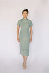 Front view of a modern green silk Cheongsam dress, which is inspired by Japanese narcissus for an elegant vintage look.