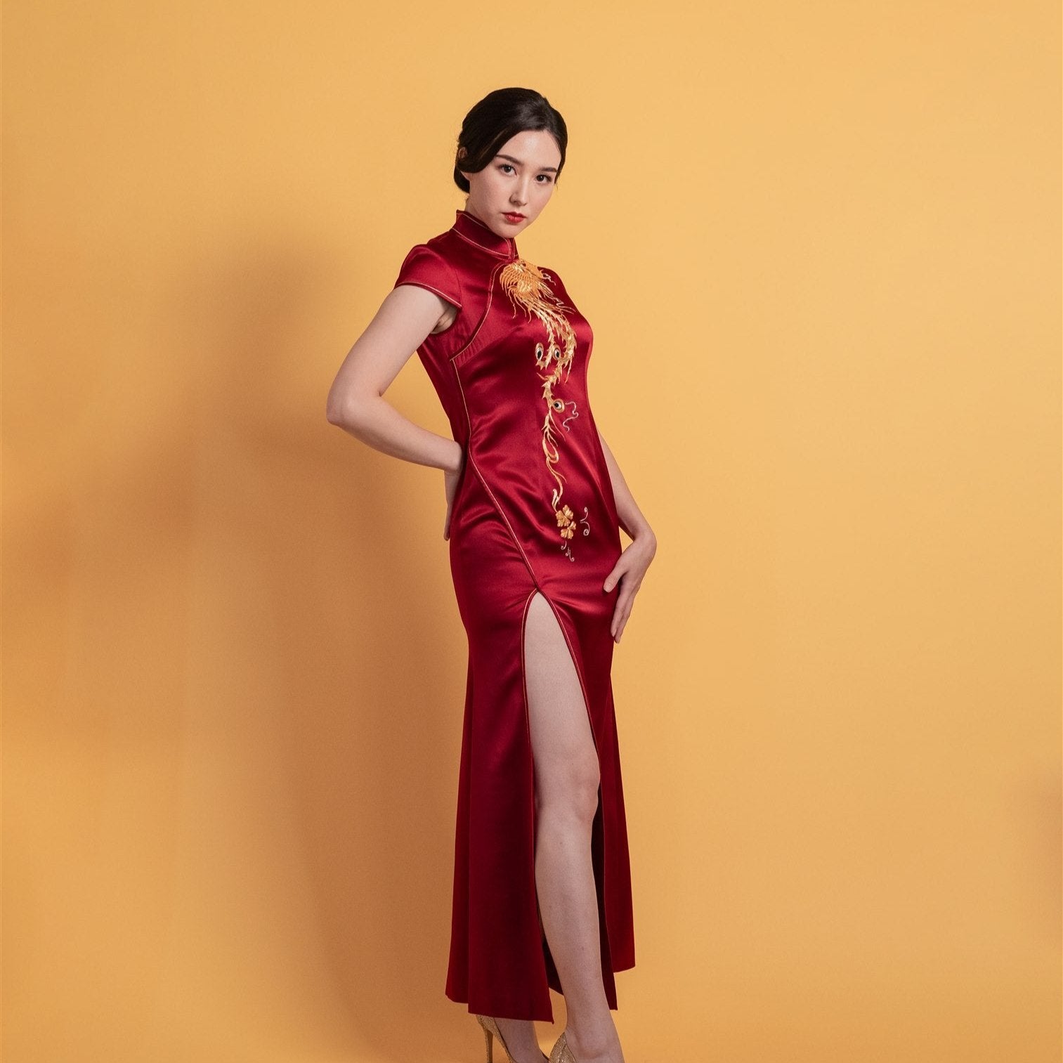 Side view of a modern mermaid Cheongsam wedding dress with a front slit, cap sleeves, and elegant gold phoenix embroidery.