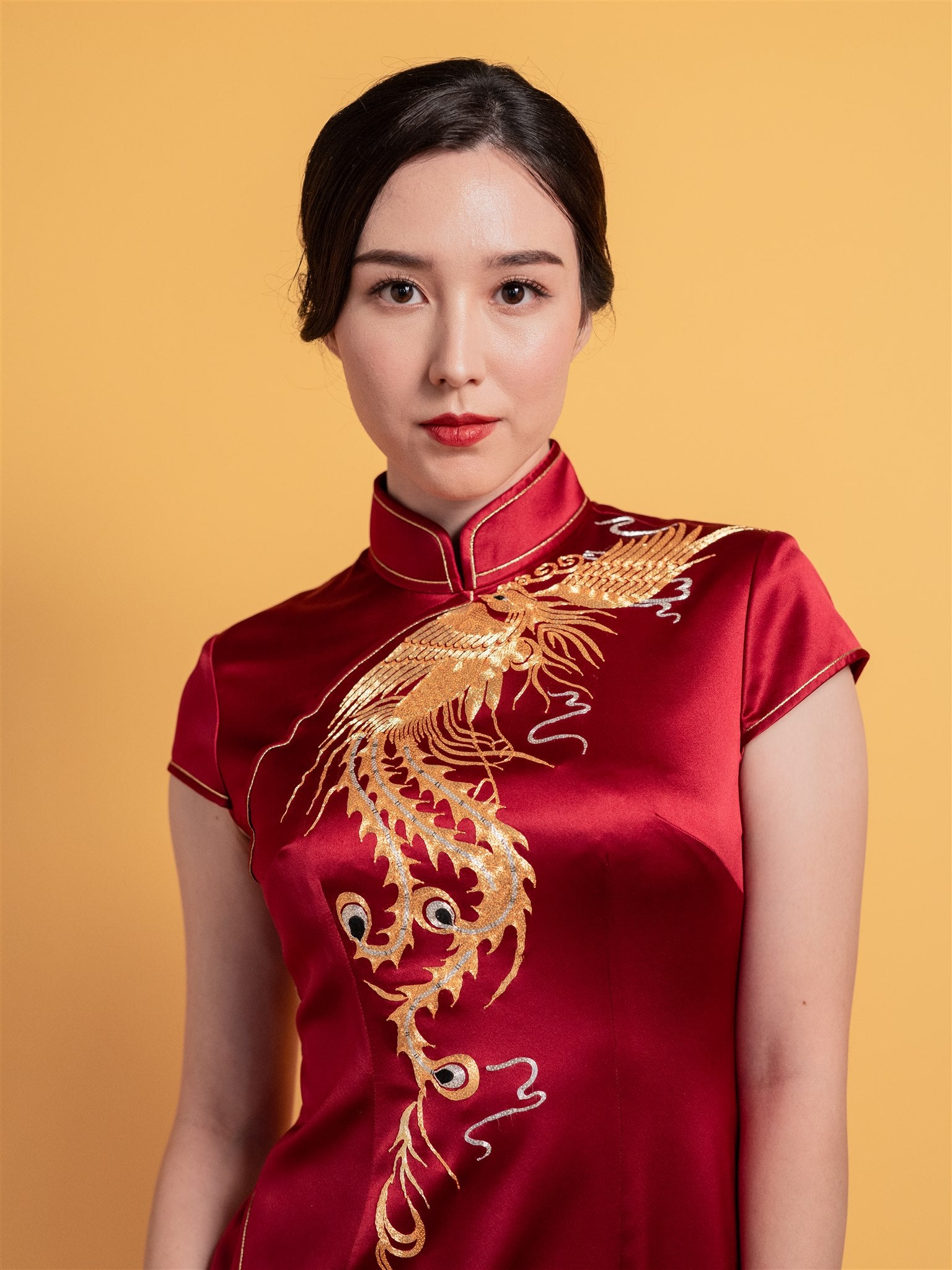 Close-up detail of the gold phoenix embroidery on a modern mermaid Cheongsam wedding dress with a front slit and cap sleeves.