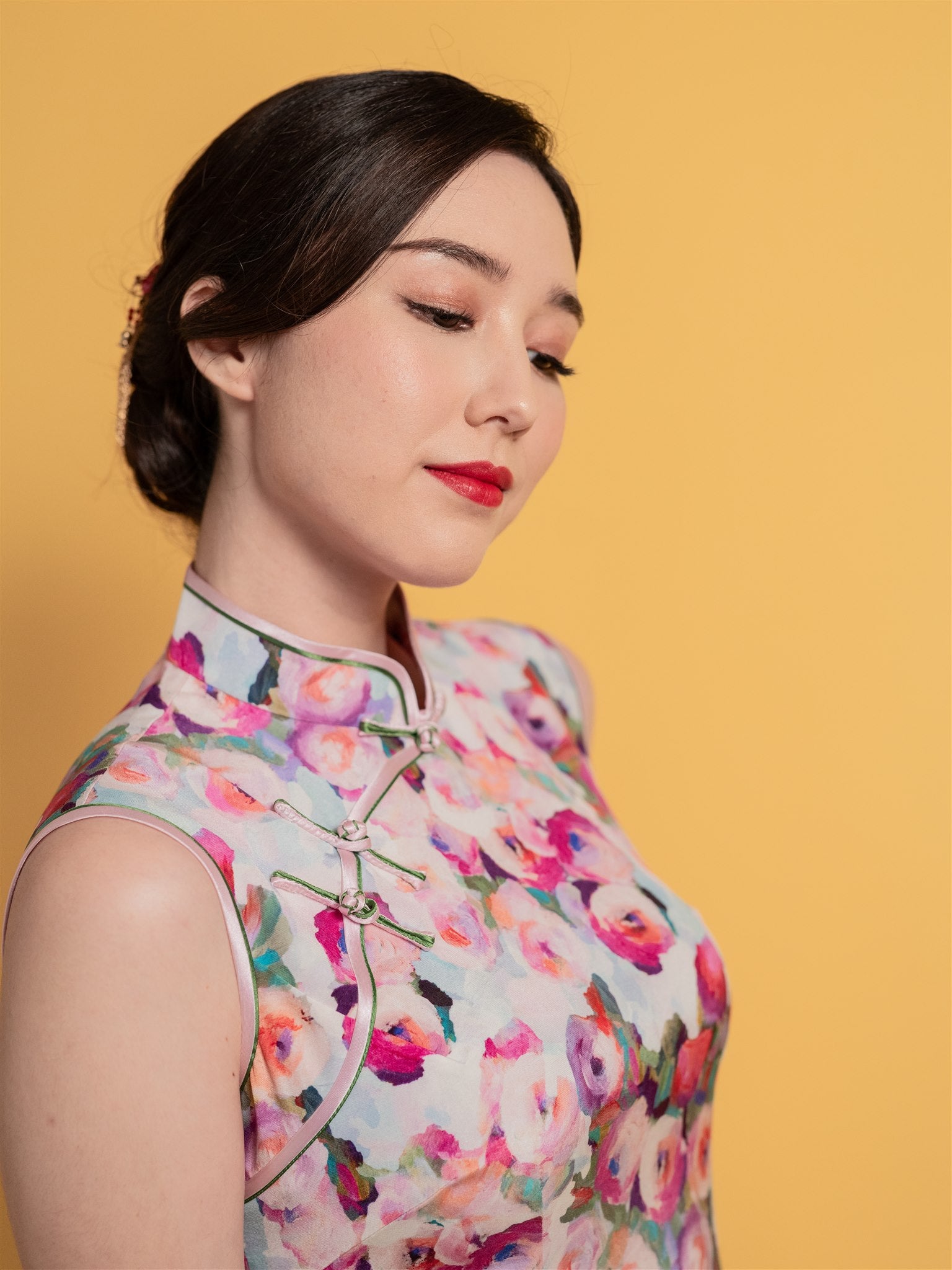 Close-up detail of the floral pattern and Pankou knot on a modern short pink silk Cheongsam with a sleeveless design, perfect for a fun and versatile style.