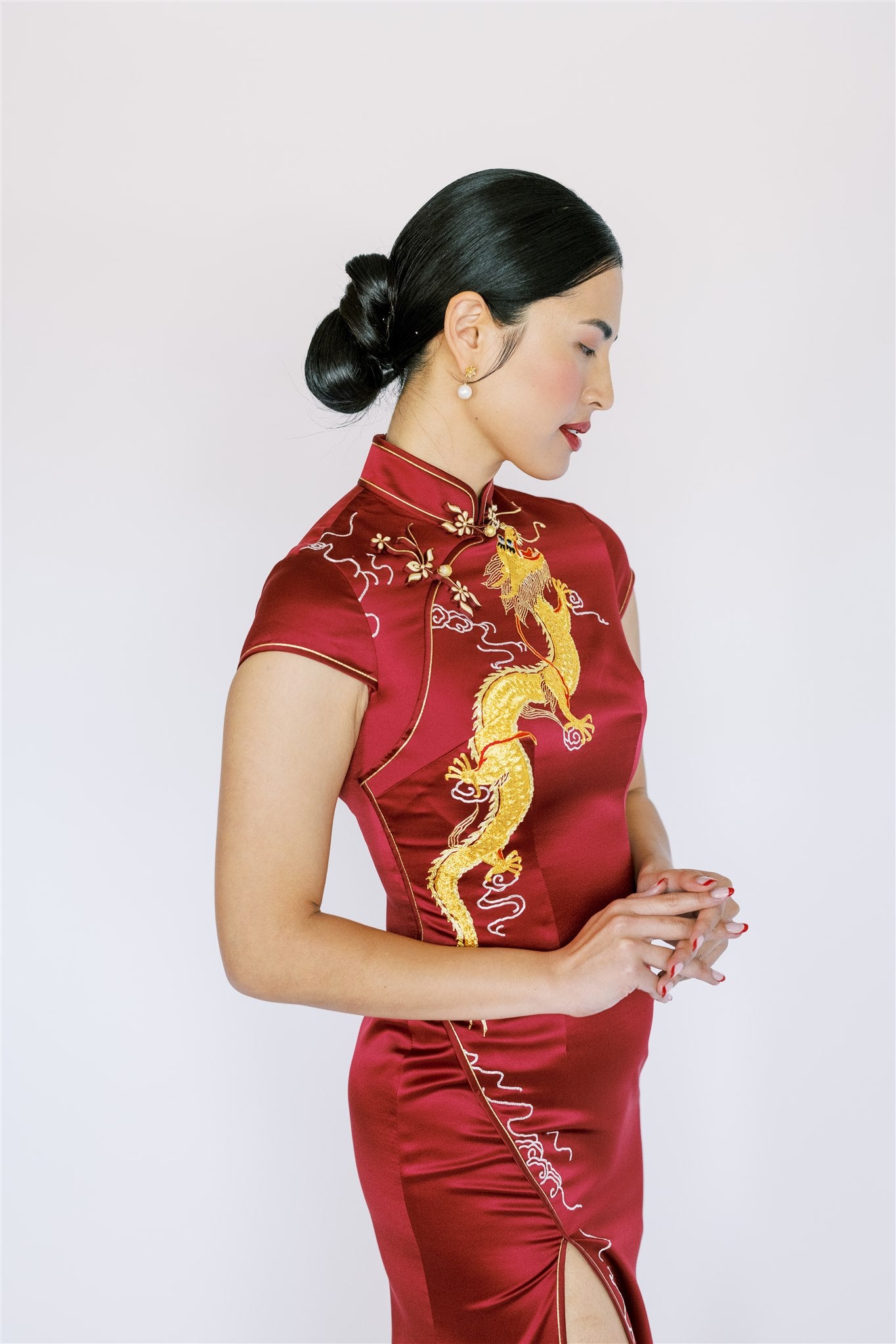 A woman wearing wine red silk Qipao with gold dragon and hand-weaven pankou knot