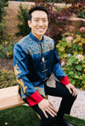 A groom wearing a navy blue tang suit with gold embroidered cloud, dragon and koi fishes