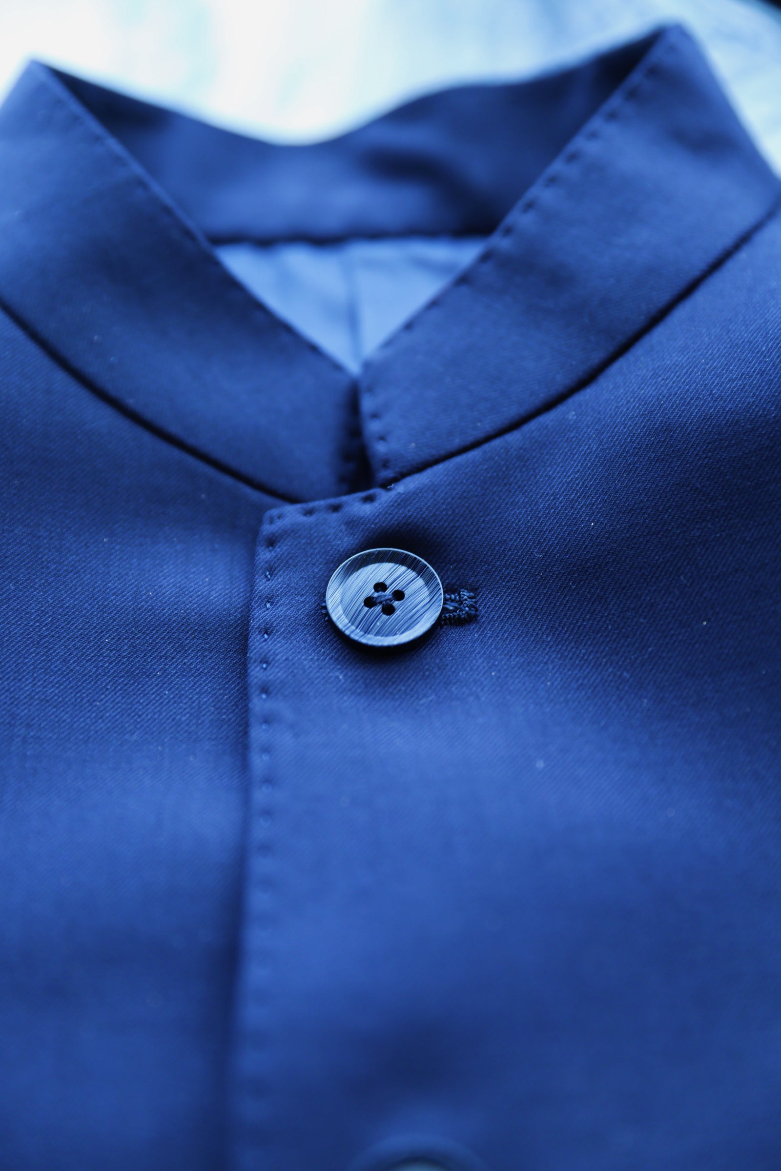 Close-up of Mandarin collar and front button detailing on navy Italian wool Zhongshan suit.