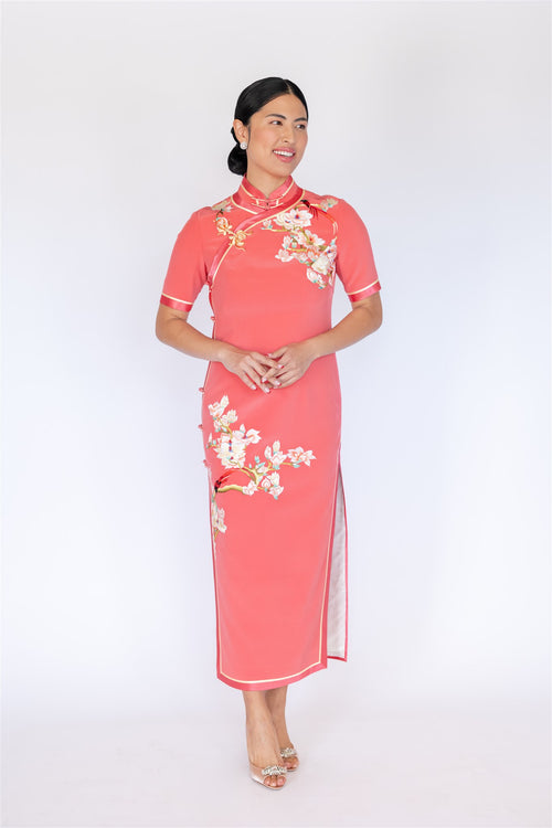 Orange pink silk Cheongsam with cherry blossom embroidery and yellow trim, front view.