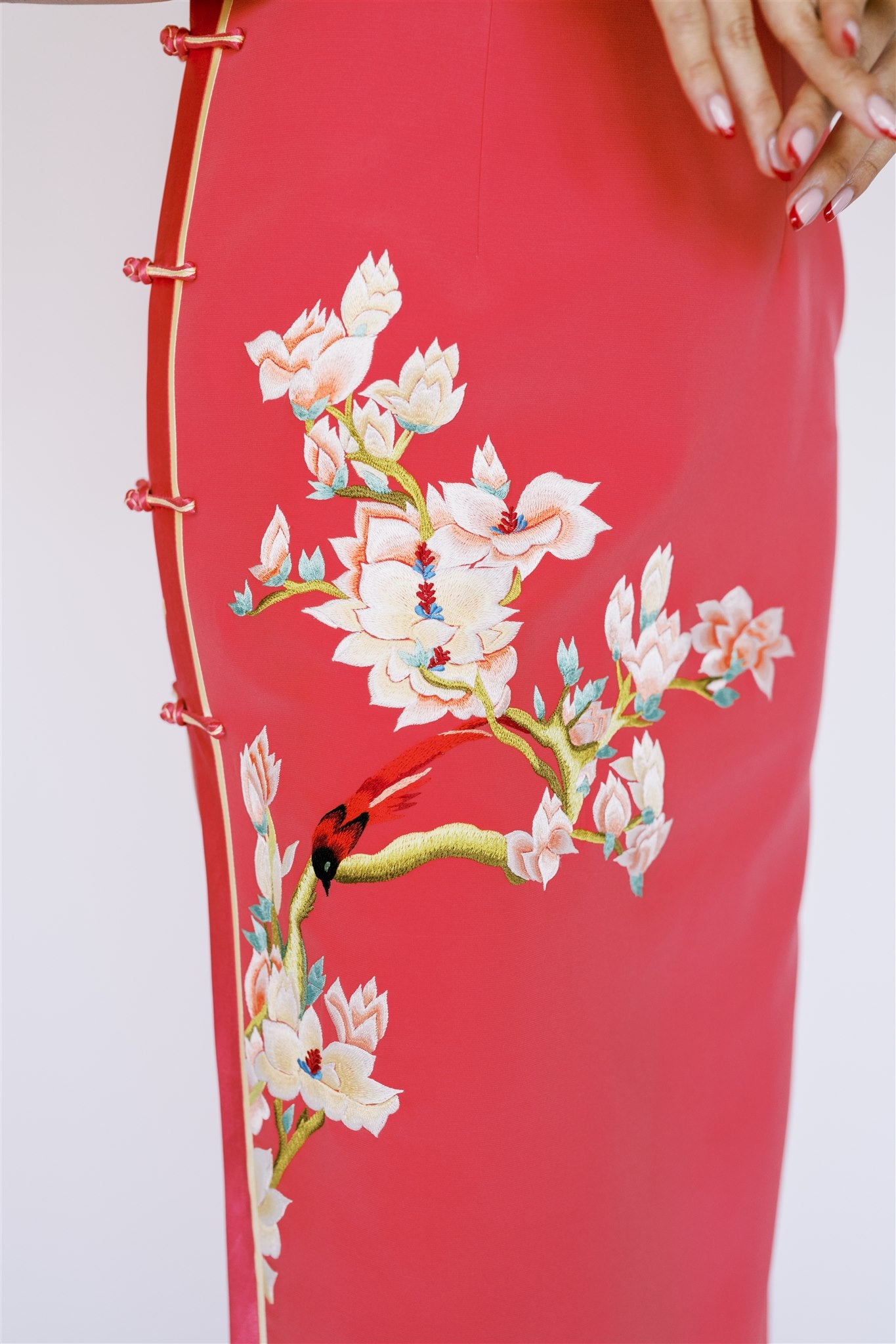 A woman wearing an orange silk Cheongsam with side slit and magnolia flowers and bird