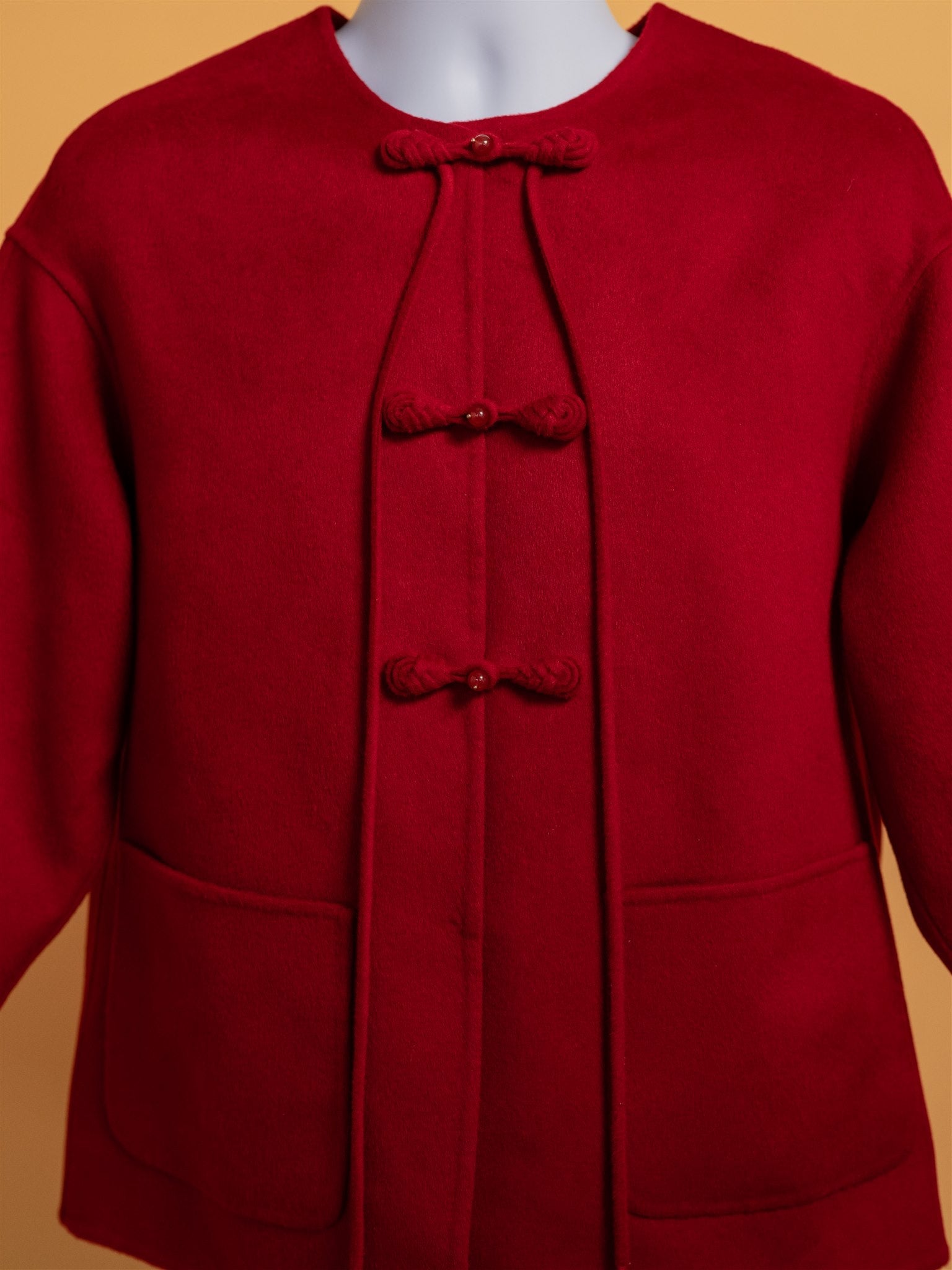 Close-up image of the Pankou Knot buttons and pockets on an oversized red wool tang suit jacket. 