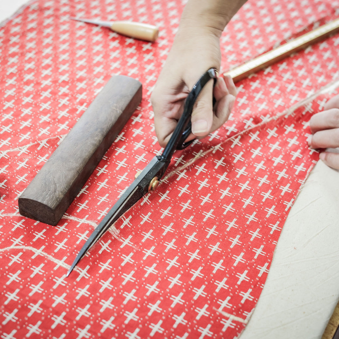 A seamstress is cutting a pattern to make a custom Qipao