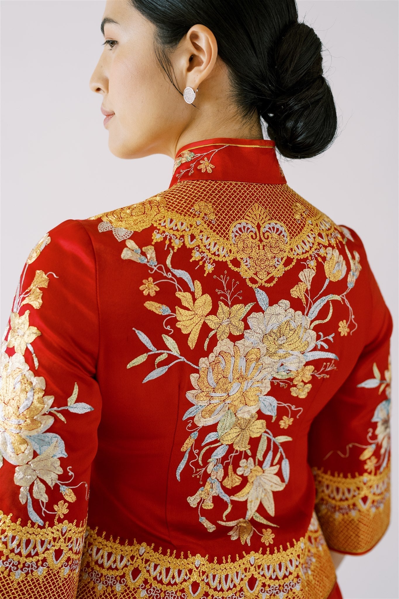 A woman wearing a red Xiu He Fu fitted jacket with gold, blue and silver peonies embroidery