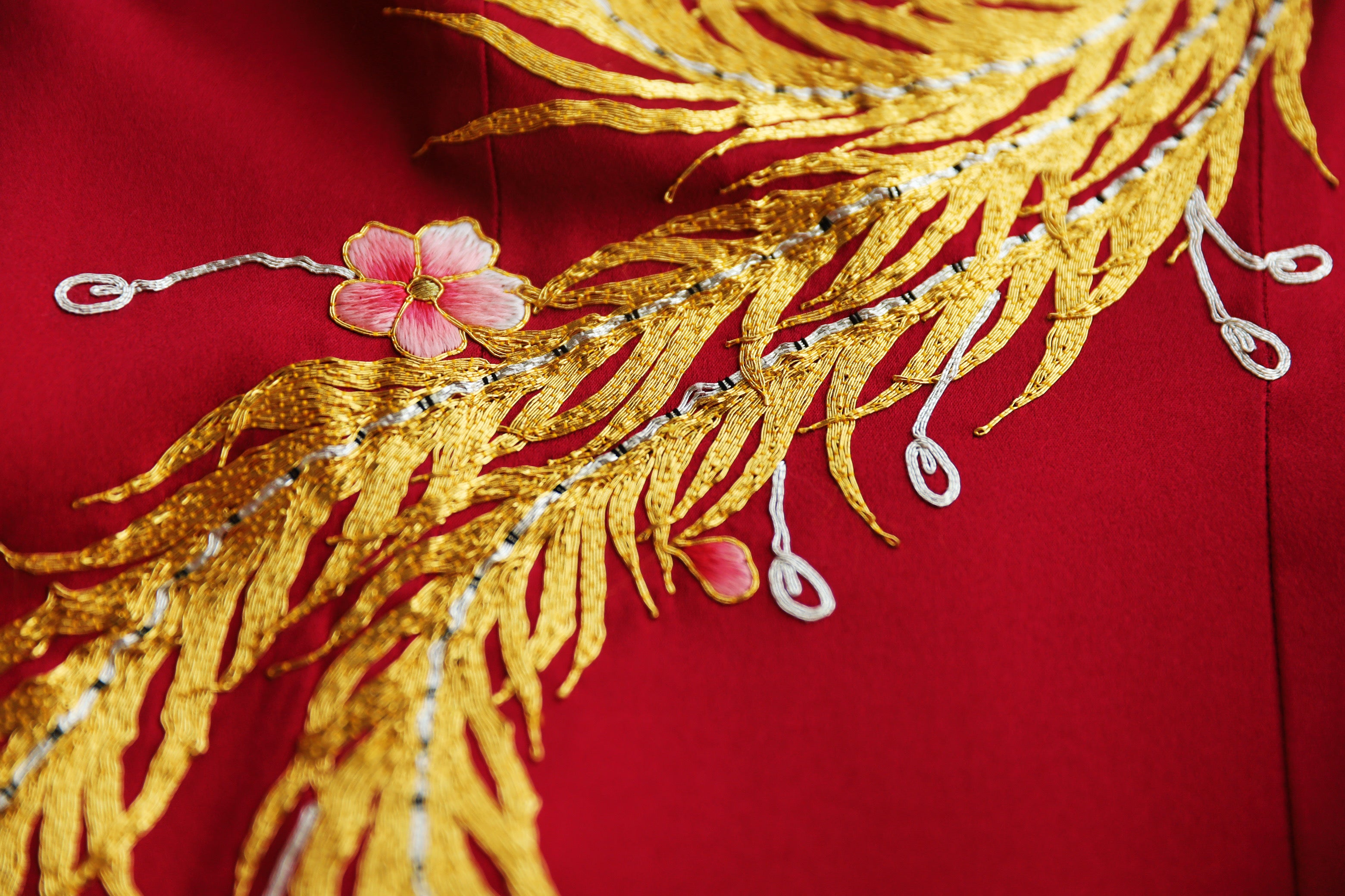 Close-up of peony and Panjin hand-embroidered phoenix on a wine red Chinese wedding tea ceremony dress