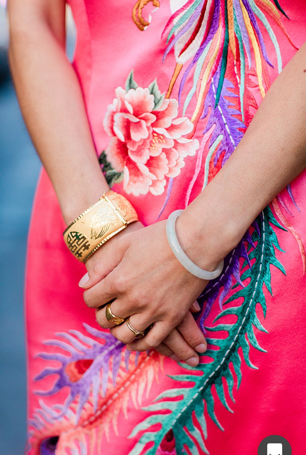 Close-up details of hand-embroidered peony and phoenix on a pink Qipao at her wedding. Also the client is wearing gold bangles and jade bracelet with her red Qipao 