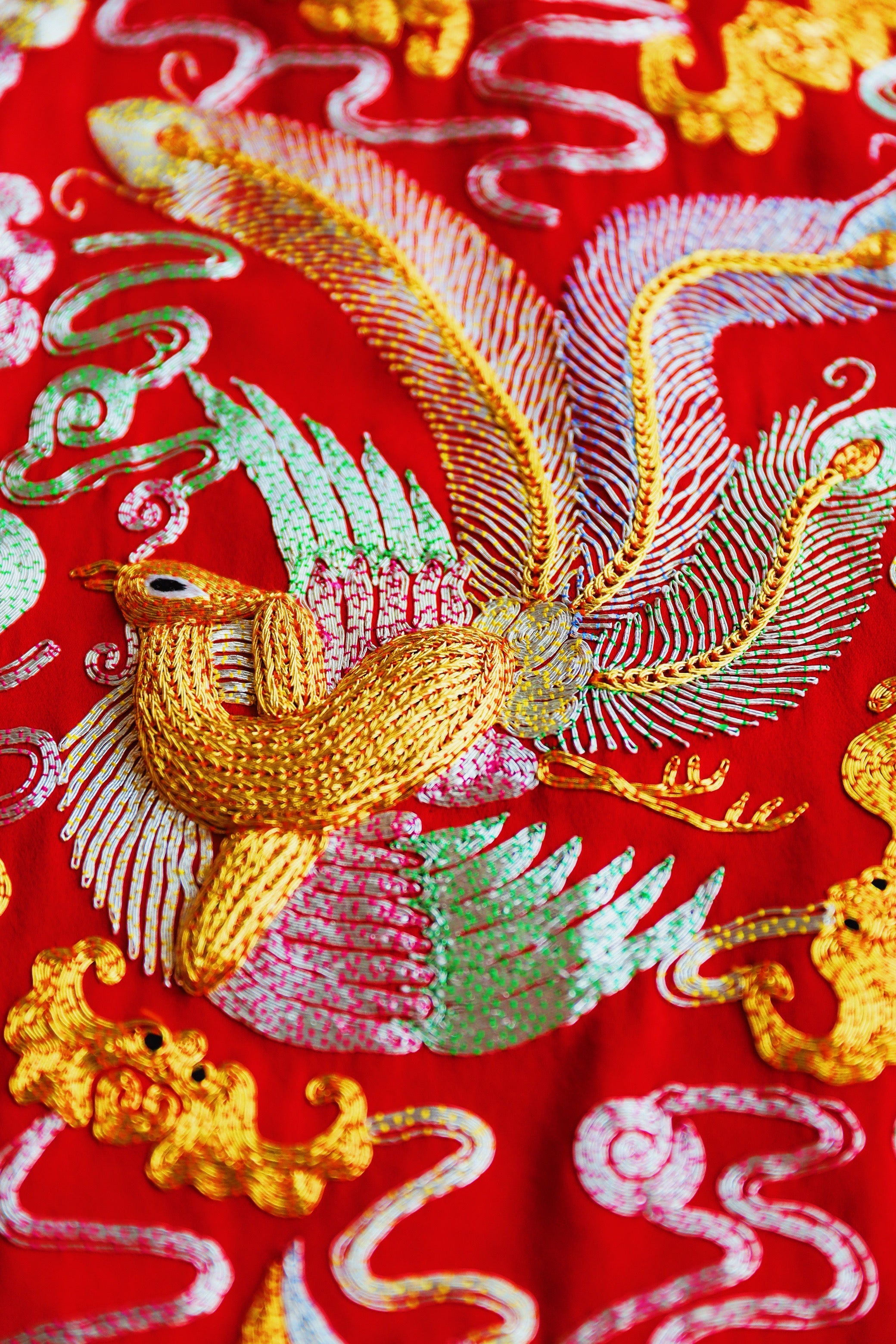 Close-up of 3D hand-embroidered gold and silver phoenix details on a red traditional Chinese Wedding Dress.