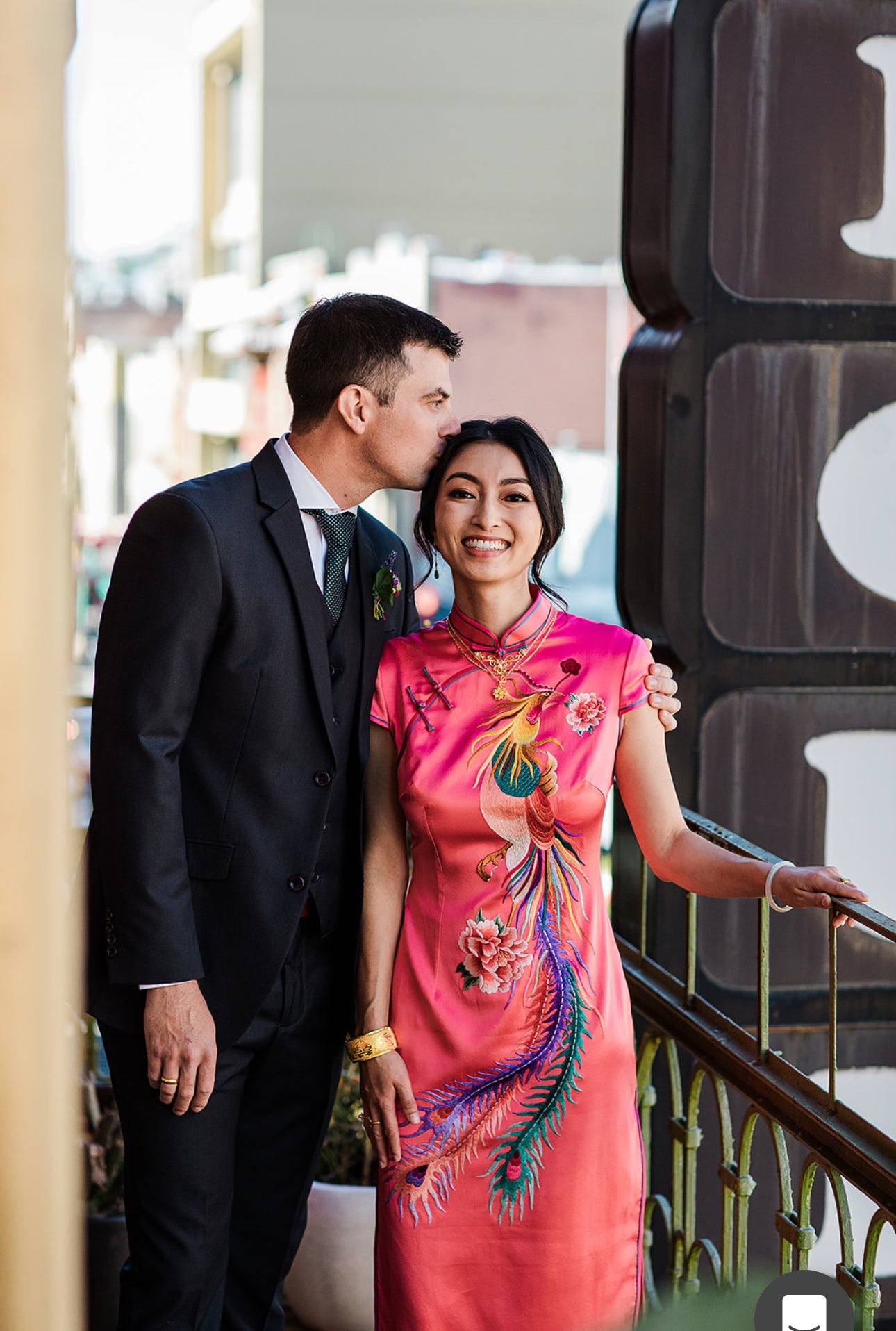 A woman is wearing a pink silk Cheongsam with peony and phoenix hand embroidery at her Chinese Tea Ceremony