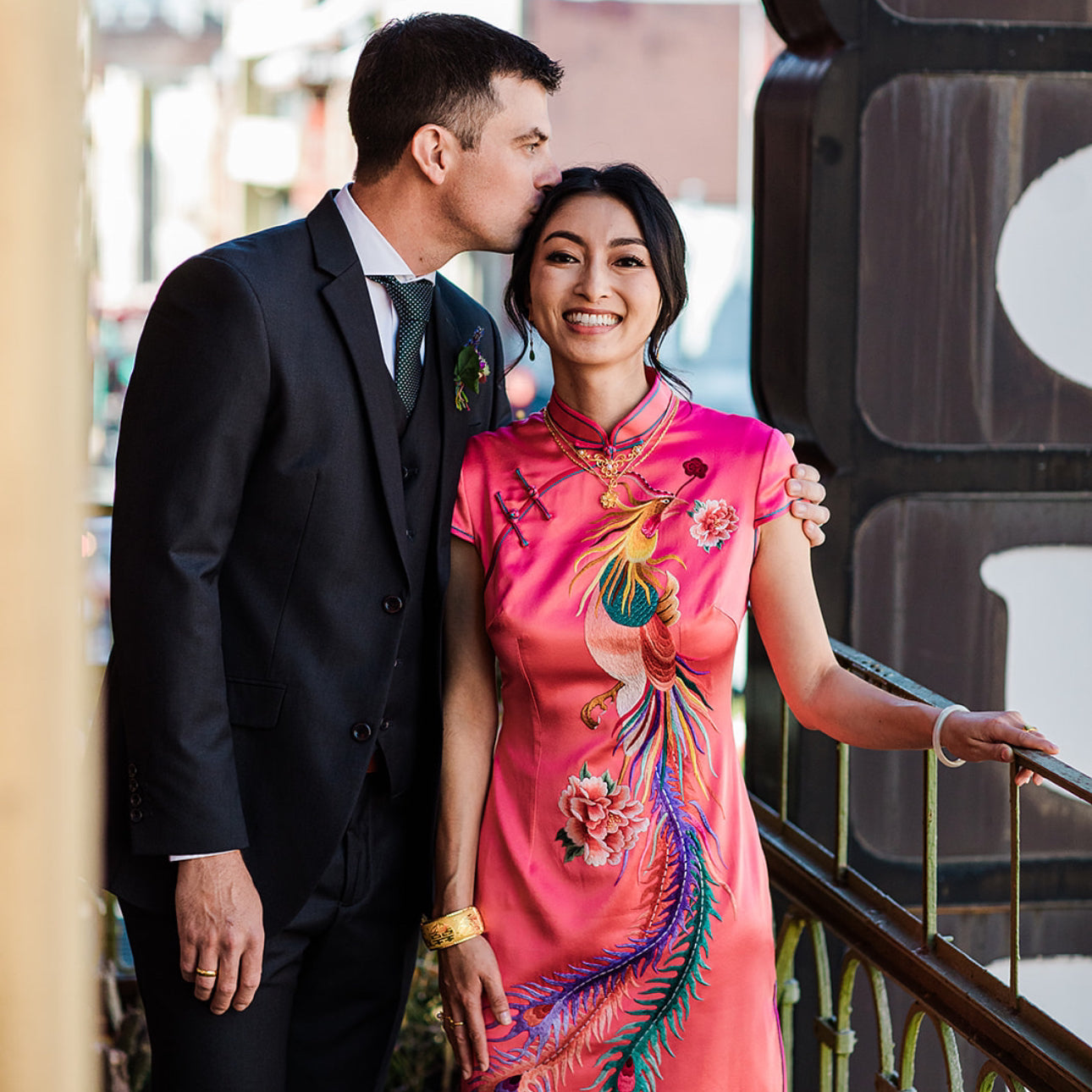 A bride wearing a pink wedding qipao with colorful phoenix and peony embroidery at her Chinese Tea Ceremony