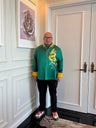 A man in a custom made green silk tang suit with gold dragon embroidery, gold calf and lucky cloud on the mandarin collar. 