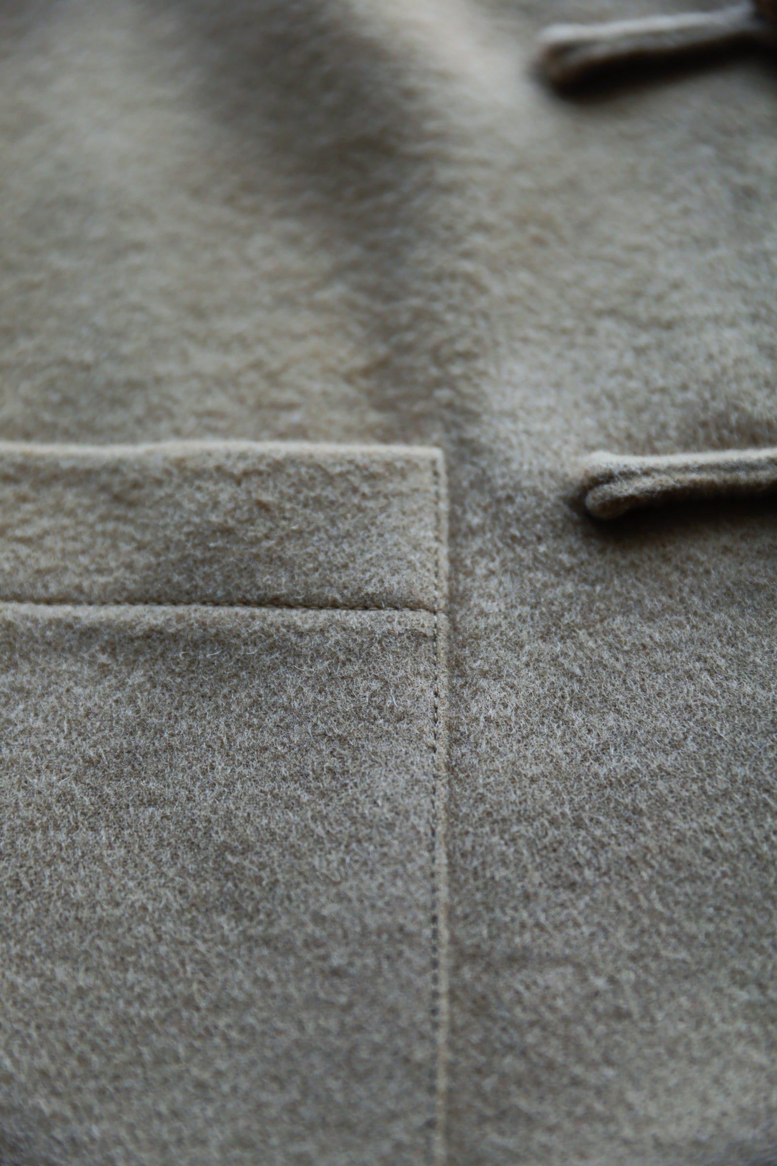 Detail of thick premium Italian wool Tang suit showing hand-finished stitching, soft brushed wool texture, and structured front pocket.
