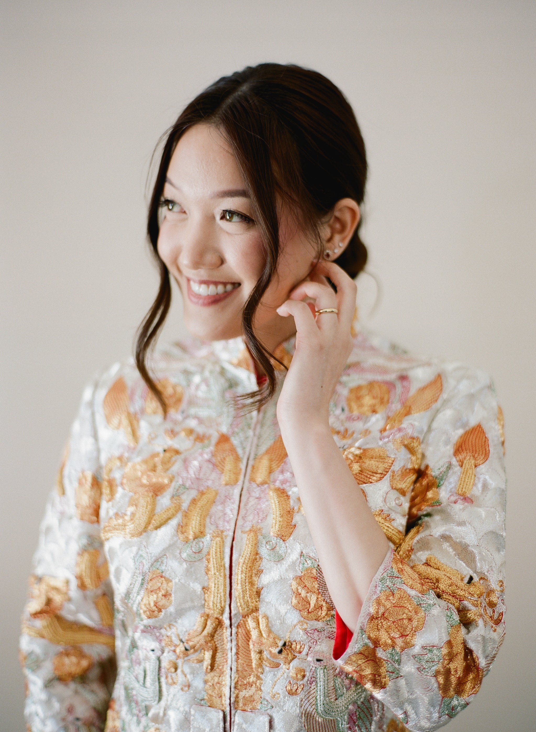 A bride wearing King Kwa Chinese Wedding Dress with gold and silver dragon and phoenix