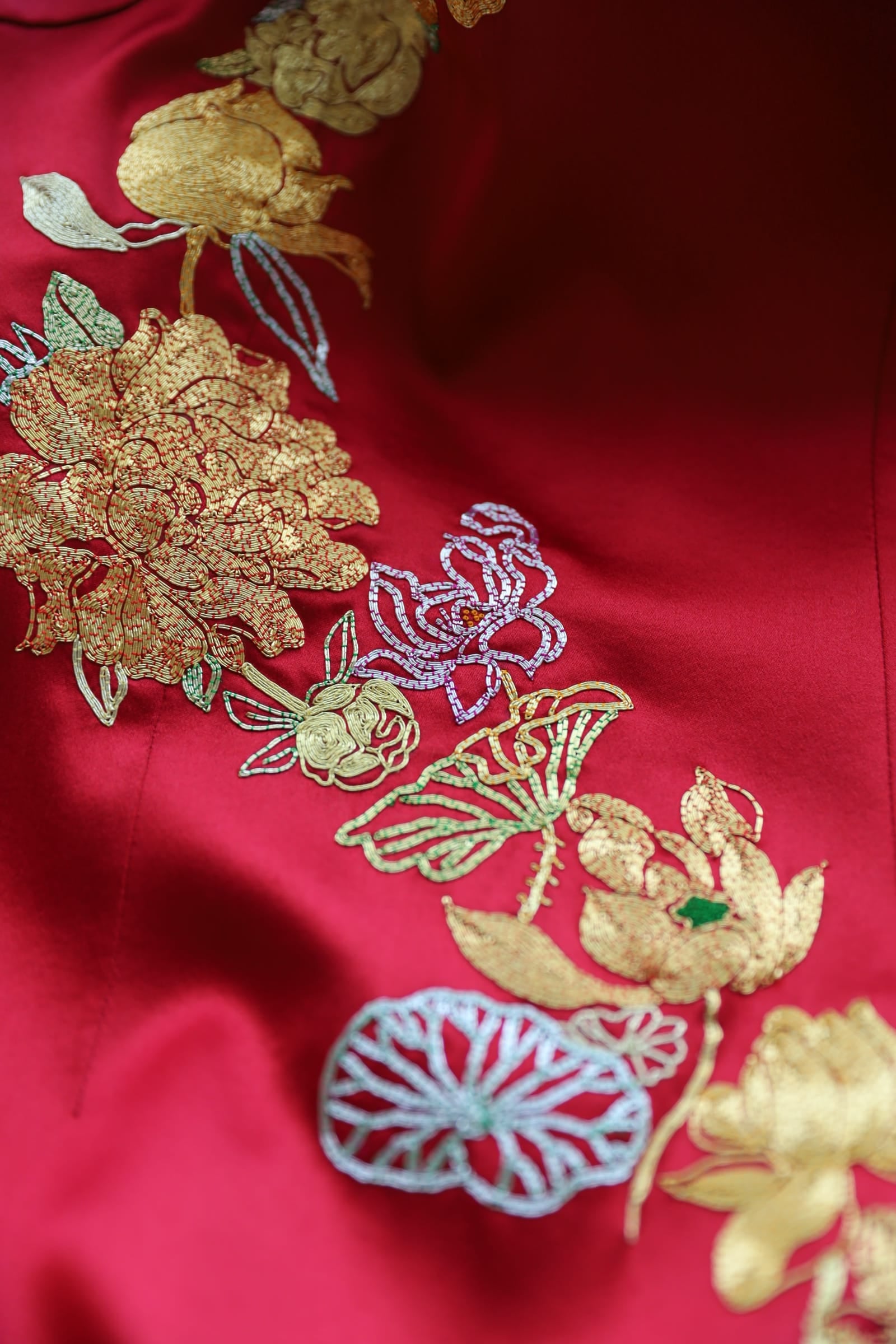 Close up of gold lotus flower and peony hand embroidery with silver leaf details on red silk Qipao, available at JINZA Los Angeles
