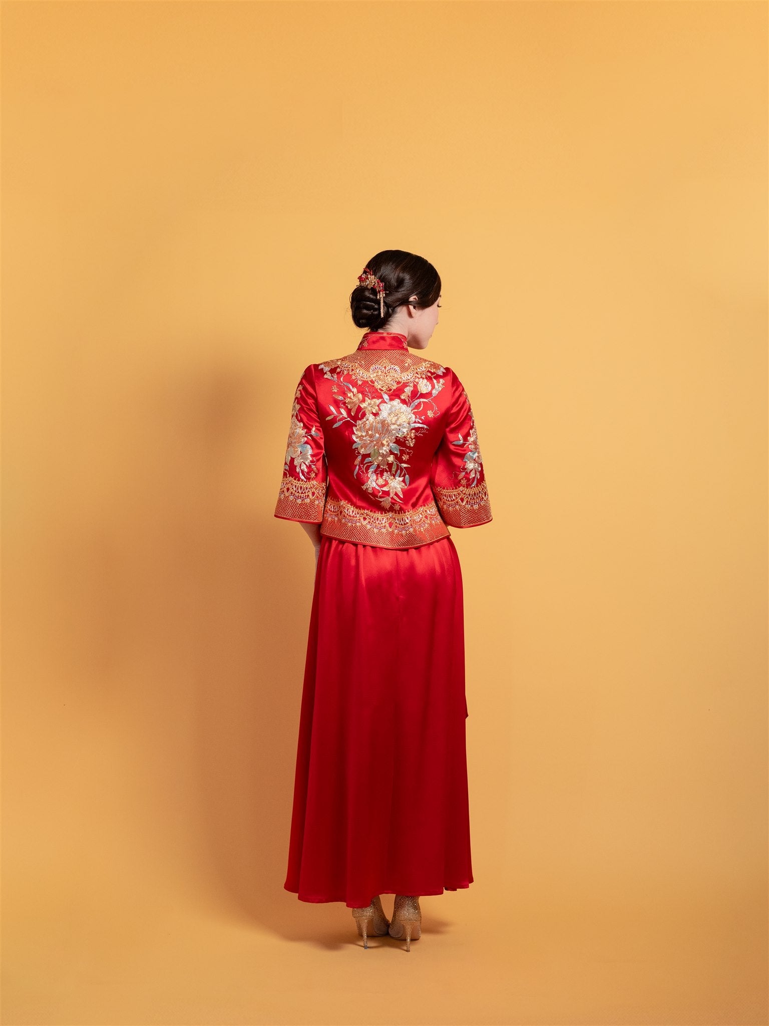 Back view of a red Xiu He Fu tea ceremony dress with peony embroidery on the fitted top and flowing A-line skirt.