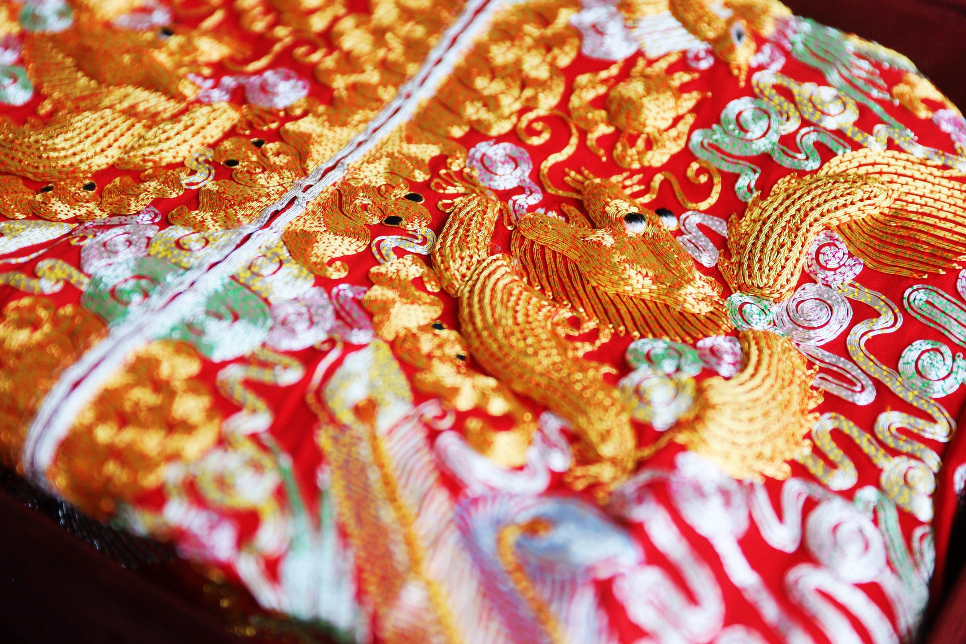 Close-up of details of 3D gold hand-embroidered dragon on a red Chinese Wedding Dress.