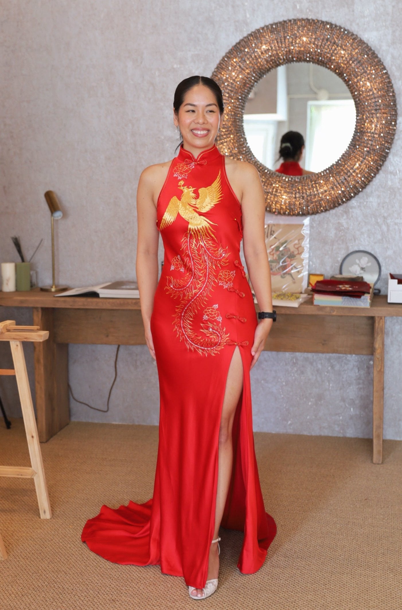 A bride wearing a modern red chinese wedding dress with halter neckline, a train and front slit. 