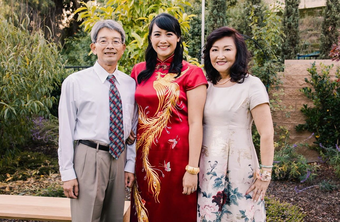 A bride wearing a red Chinese wedding dress with gold phoenix embroidery, pink butterflies and peonies