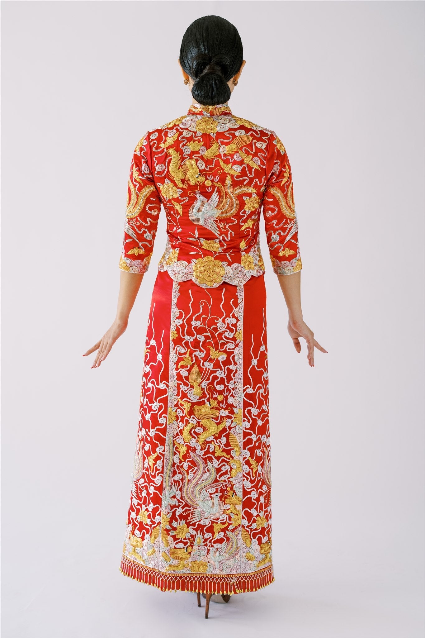 A woman wearing a red traditional Chinese Wedding Dress with dragon and phoenix embroidery