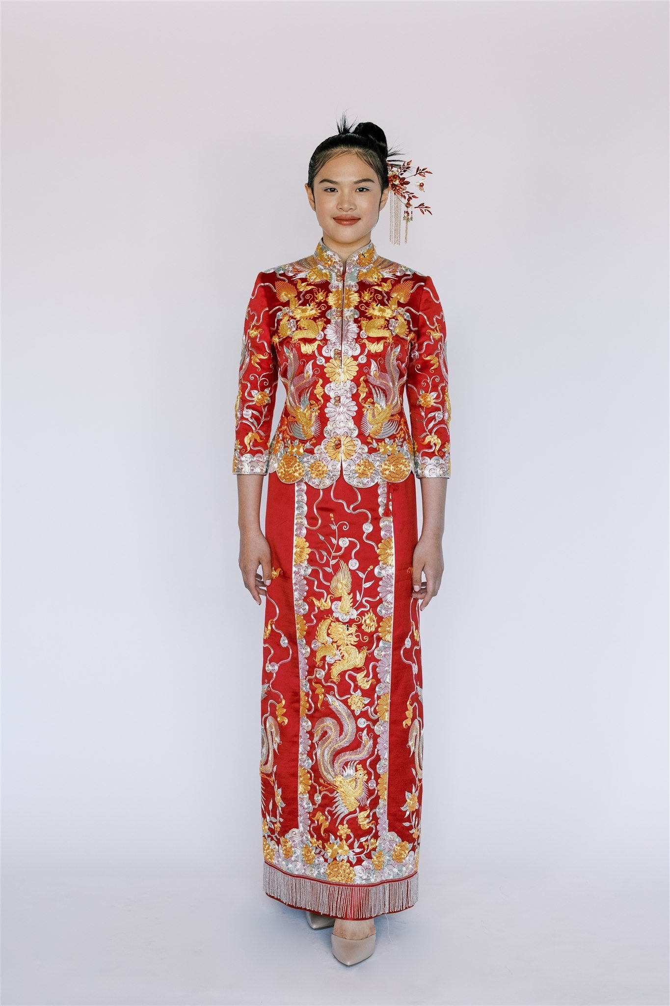 A woman wearing red traditional Chinese Wedding Dress with silver, gold and green hand embroidery