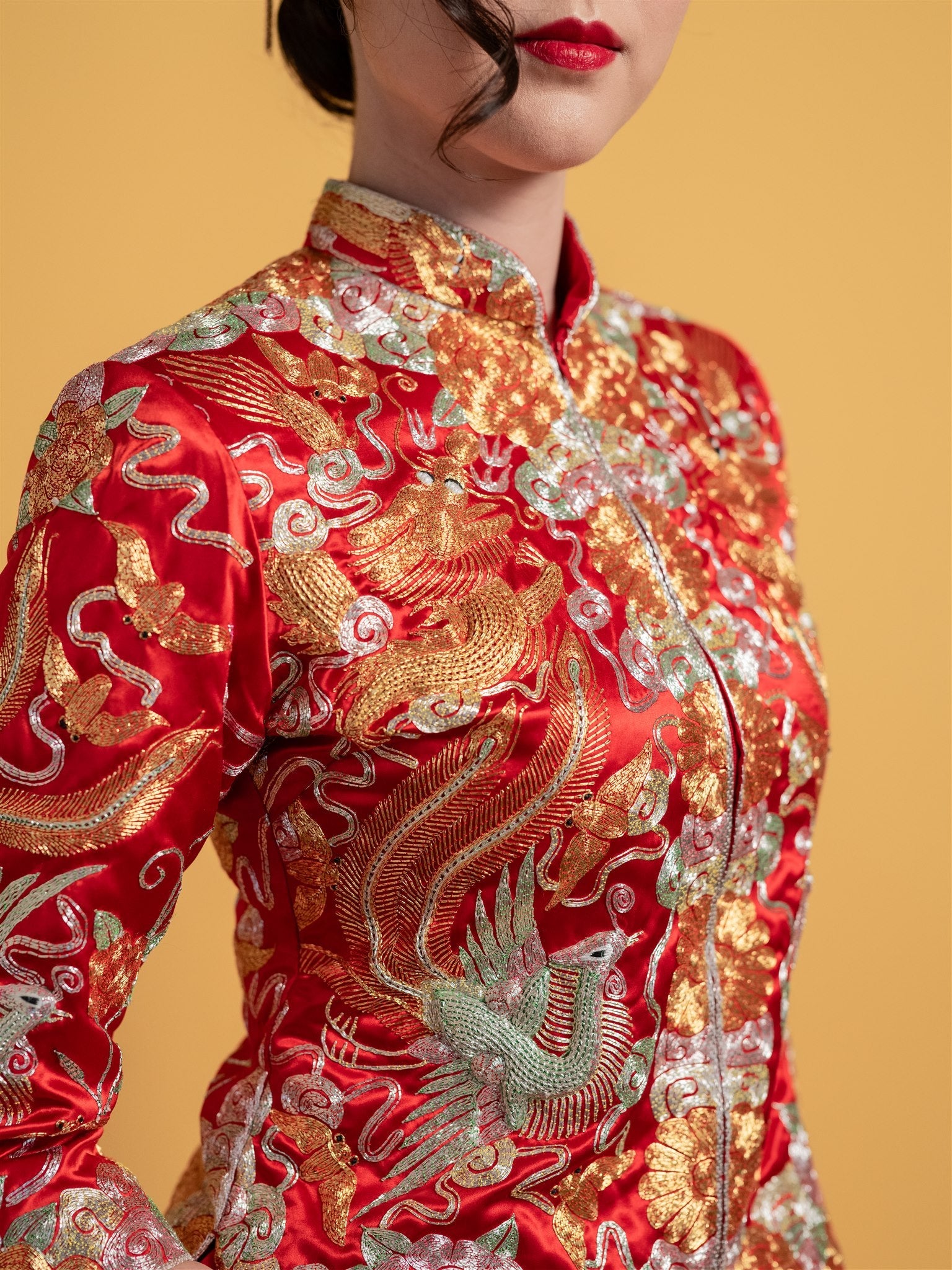 Close-up detail of the 3D hand-embroidered dragon, bat, phoenix, and clouds on a red Chinese Qun Kwa Zhong Wu Fu wedding dress for traditional tea ceremonies.