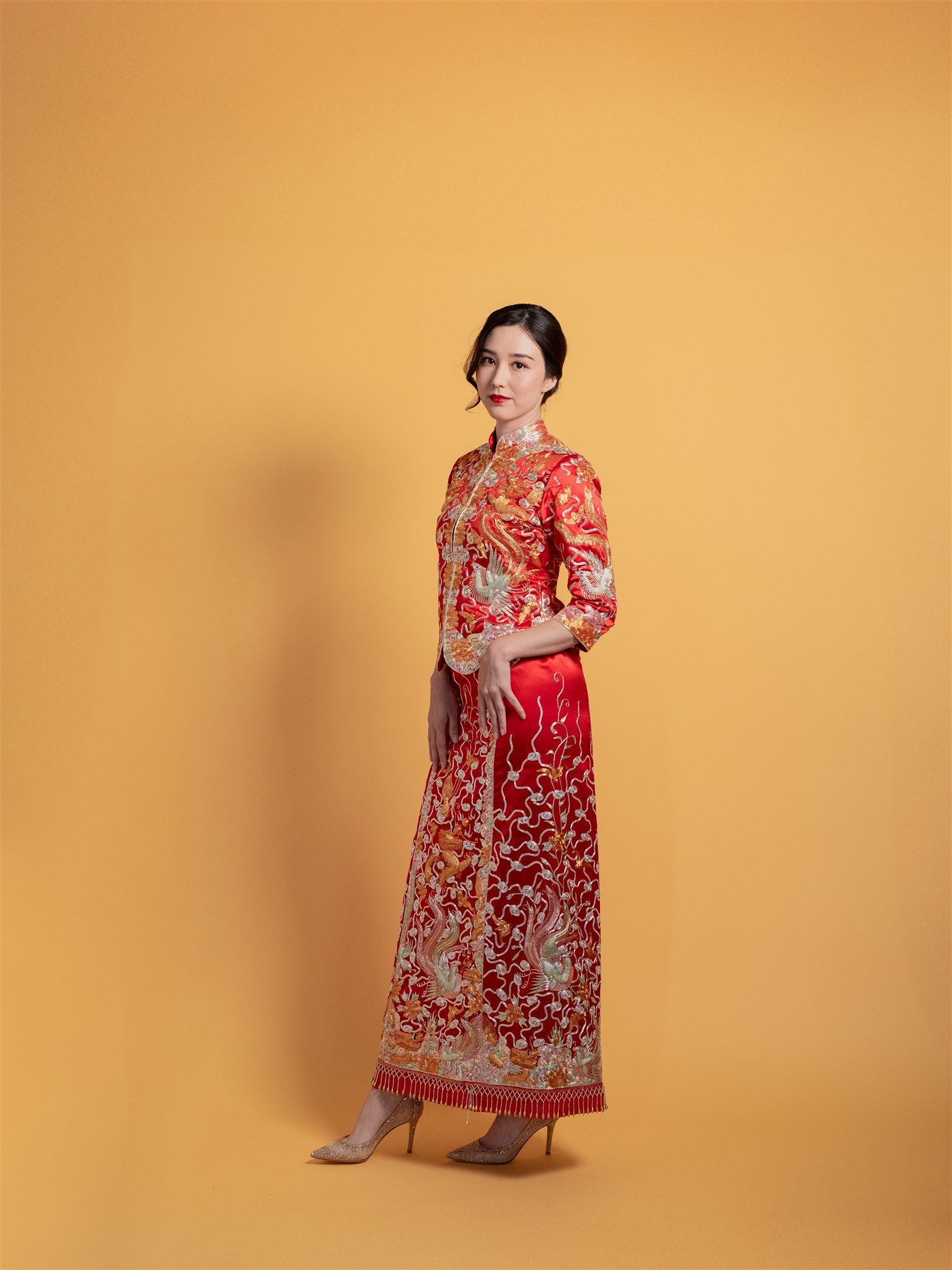 Side view of a red Qun Kwa Zhong Wu Fu wedding dress showcasing intricate 3D hand embroidery of dragon, bat, phoenix, and clouds, ideal for tea ceremonies.