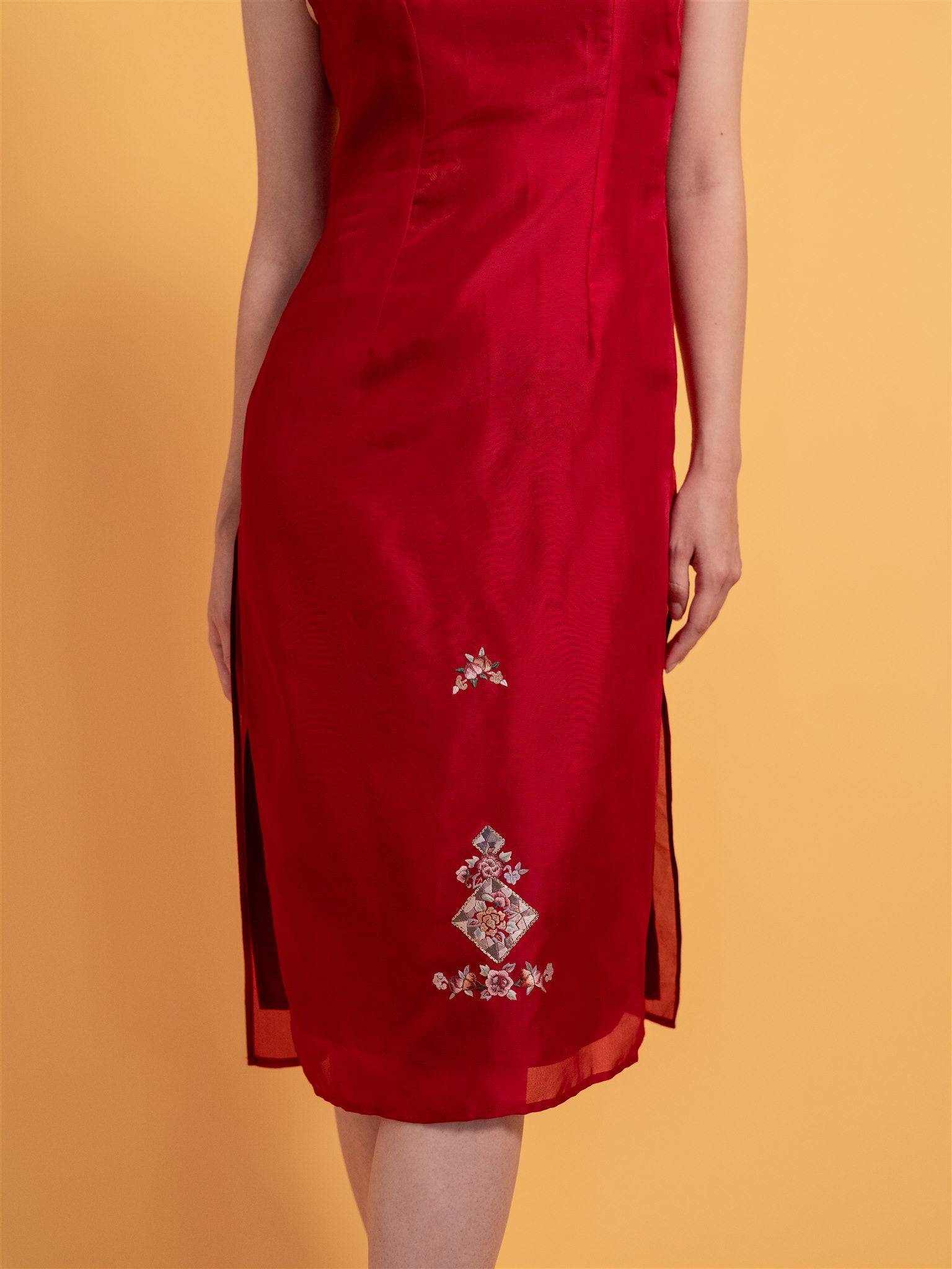 Close-up detail of the red silk organza fabric on an A-line Cheongsam dress, sleeveless and designed for a minimalist bride’s reception outfit.