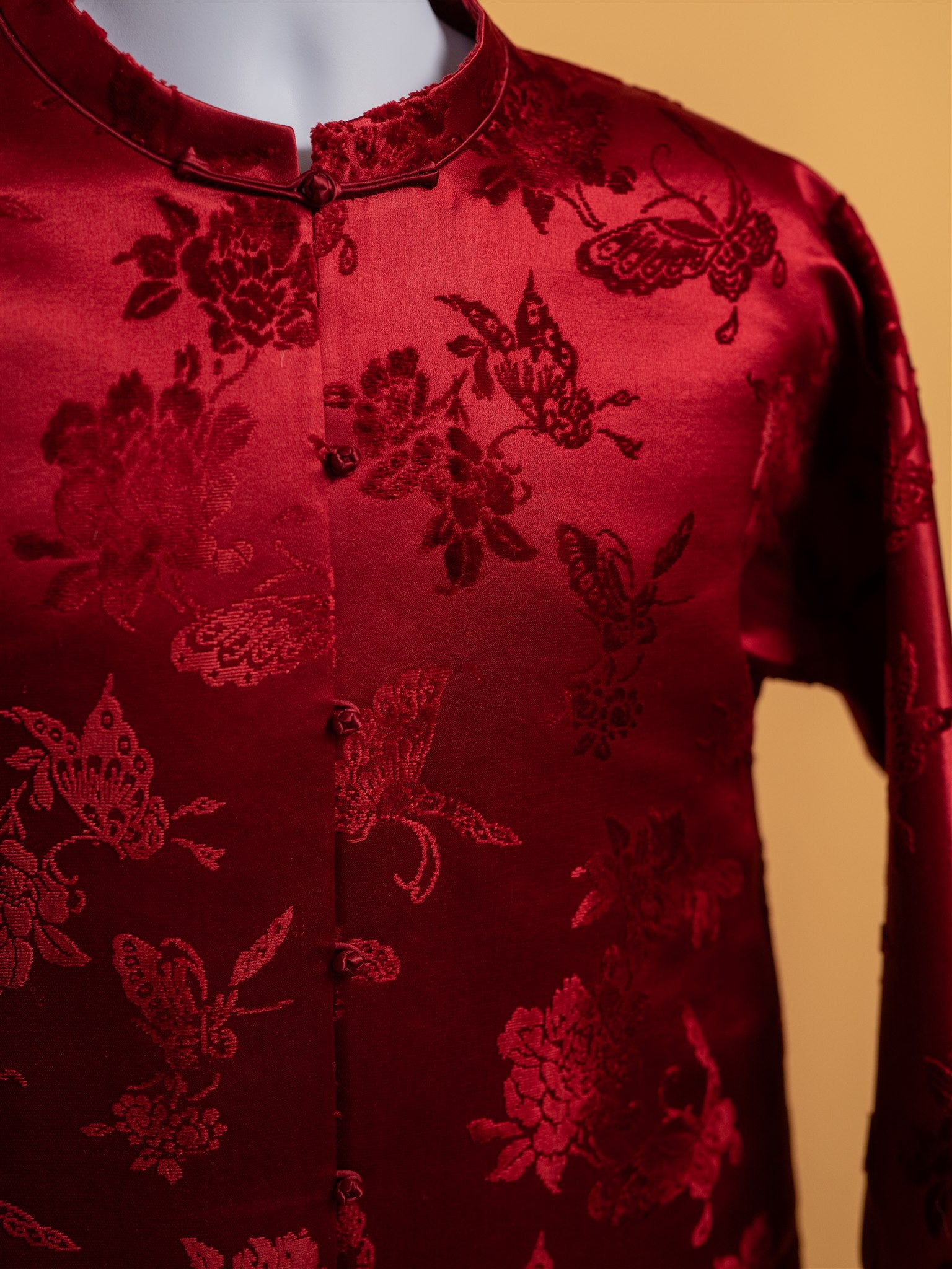 A detailed image of peony and butterfly pattern on a red silk tang suit jacket for woman, perfect for lunar new year outfit. 