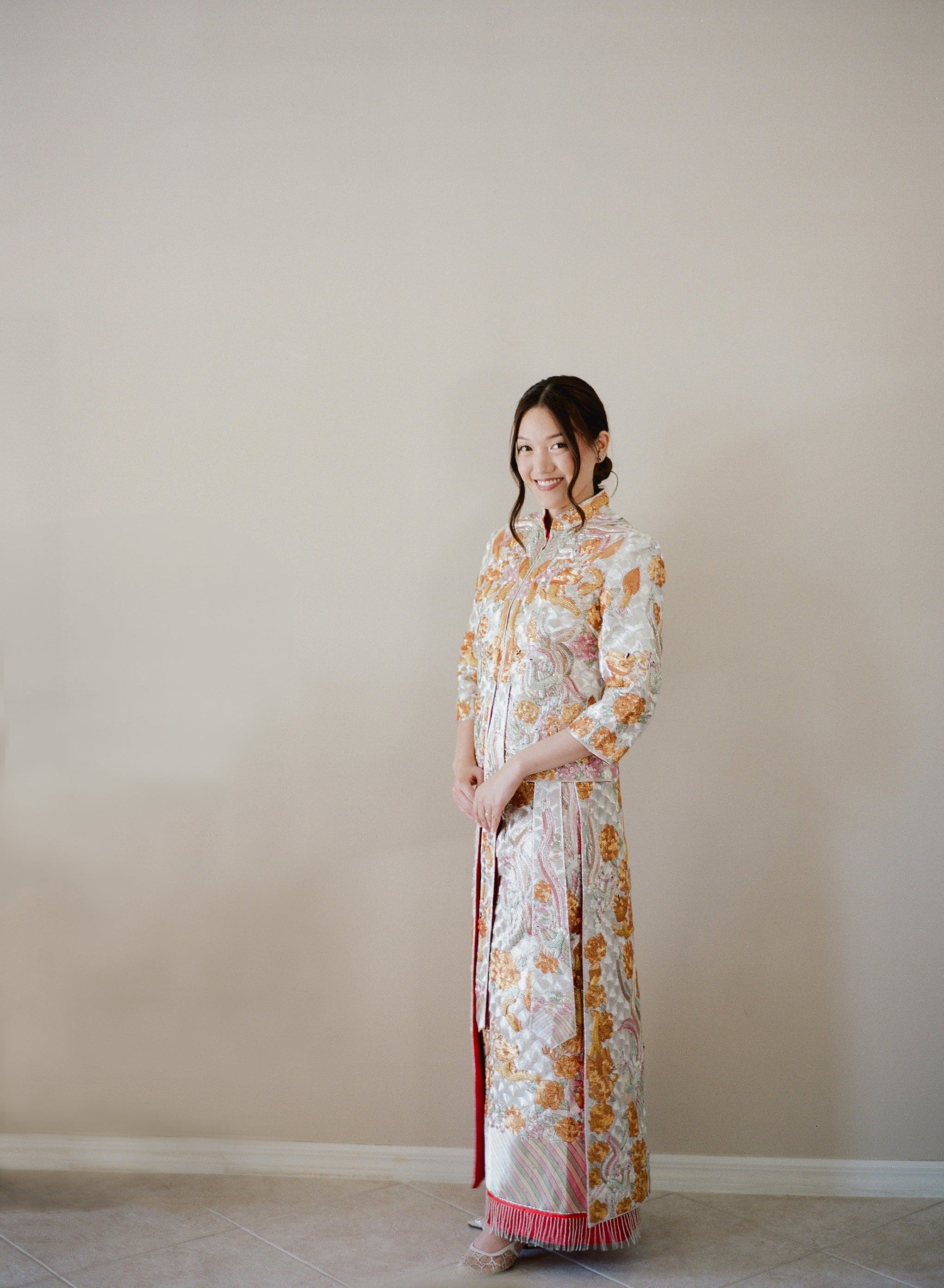 A bride wearing a red Traditional Chinese with gold dragon and phoenix embroidery and floral patterns. 